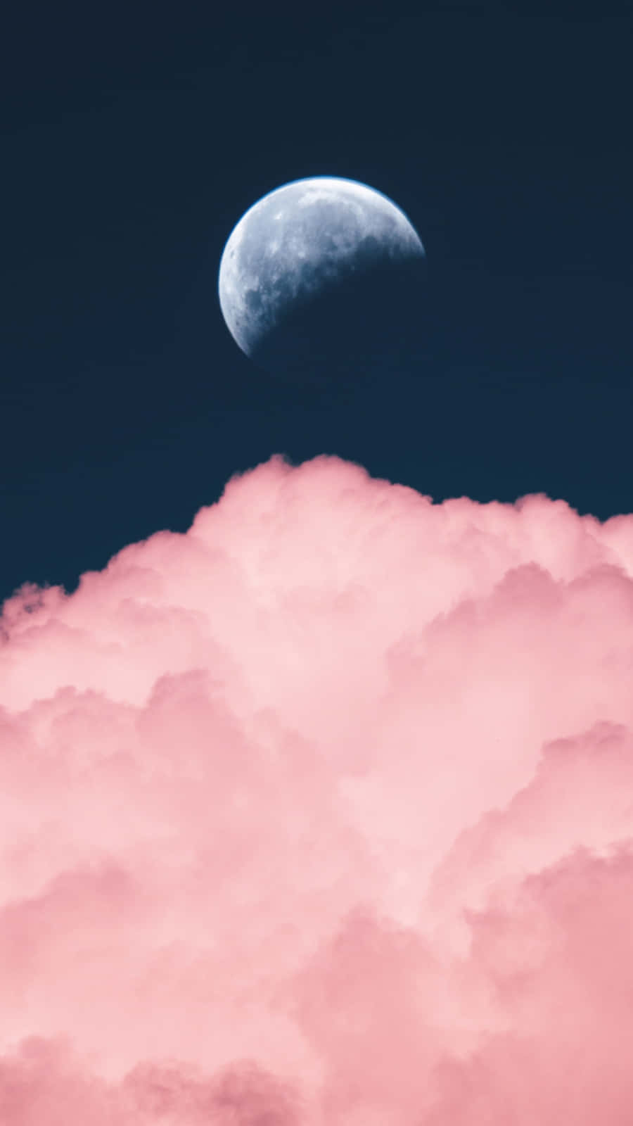 新月在粉紅雲層之上，襯托深藍夜空