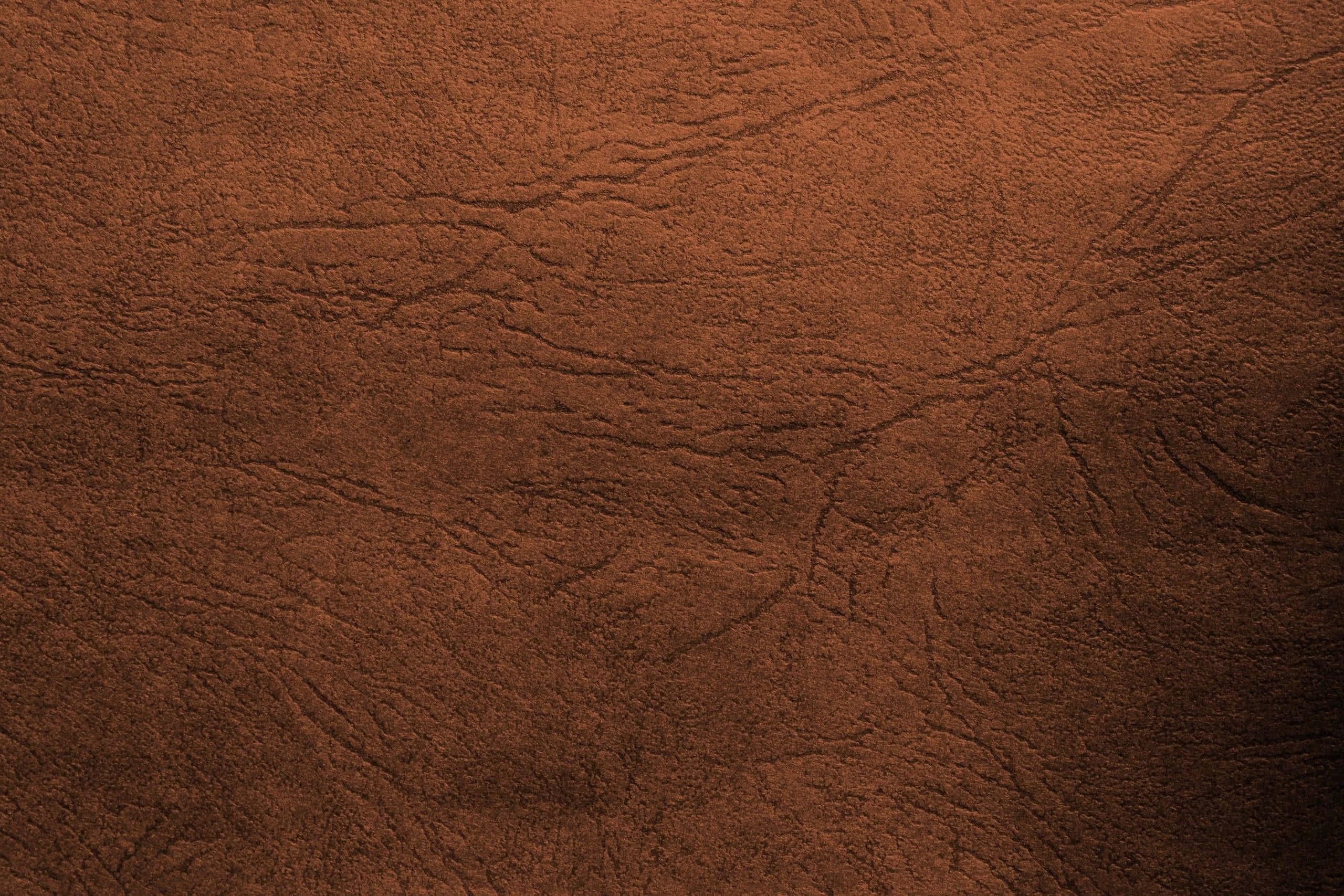 Brown Leather 桌布 壁紙 — 柔軟燈光下，豐富棕色皮革的微距特寫，展現自然皺摺與紋理顆粒。