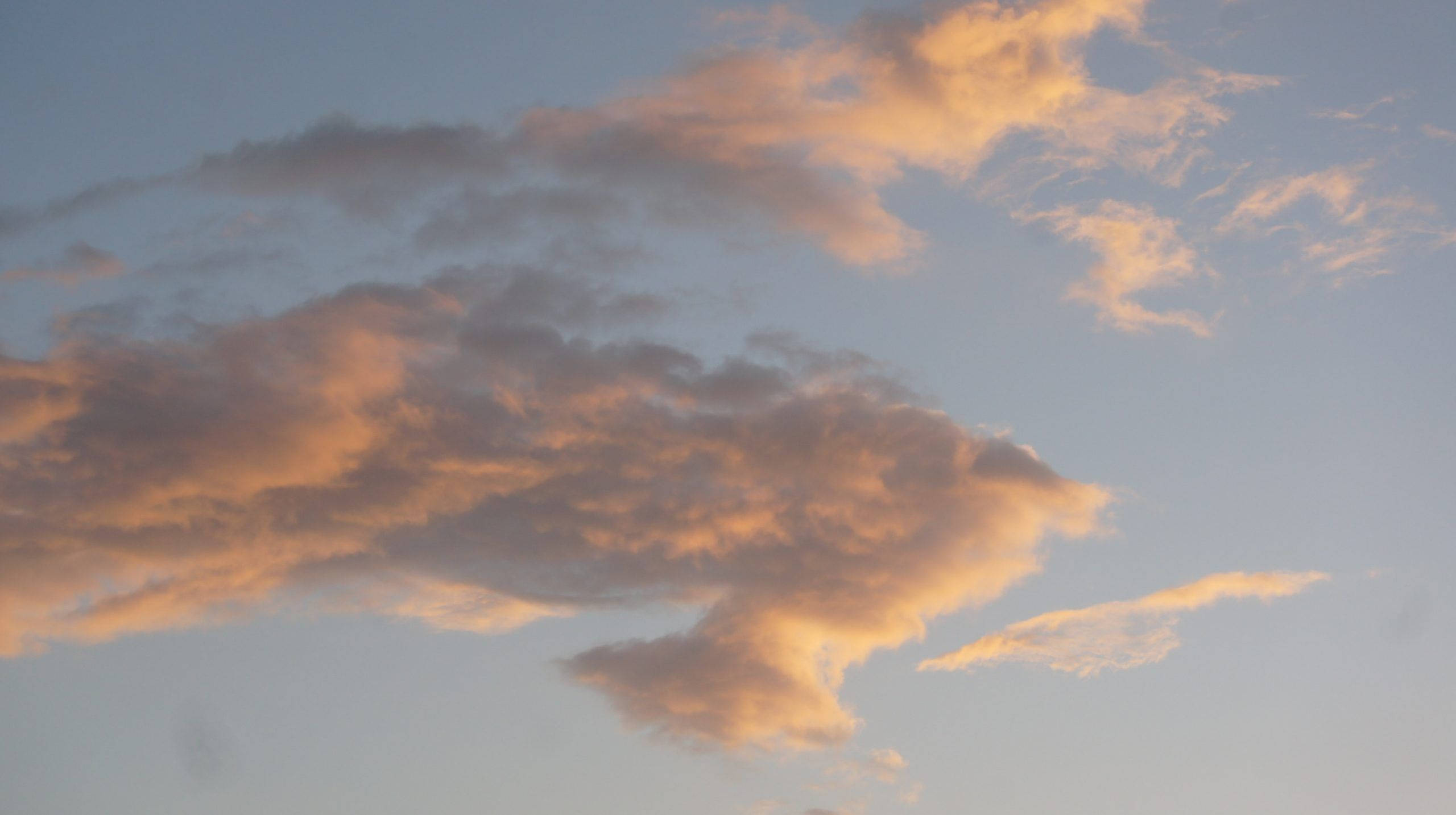 雲 桌布 壁紙 — 柔軟的雲朵在淡藍色的暮色天空中散發出溫暖的橙色和粉紅色調。