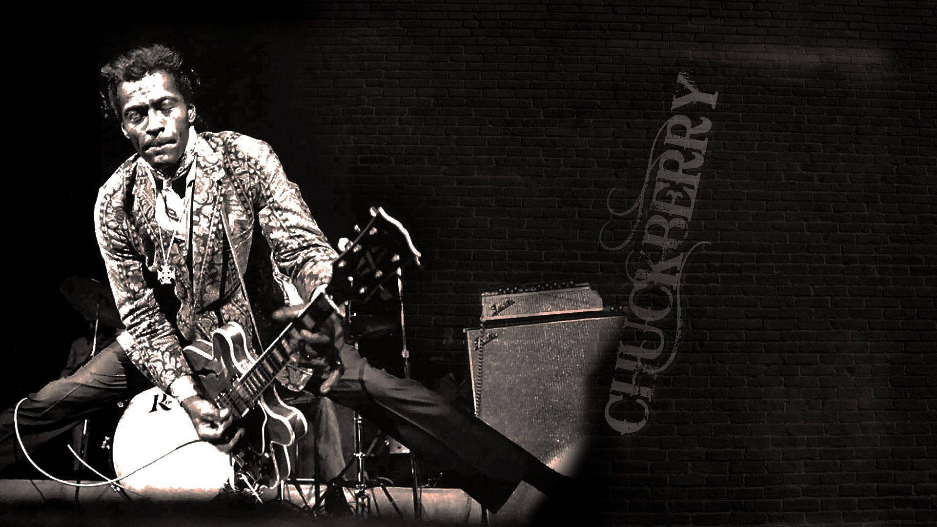 Chuck Berry 在舞台上彈結他，背景是磚牆，他的名字被寫出來。