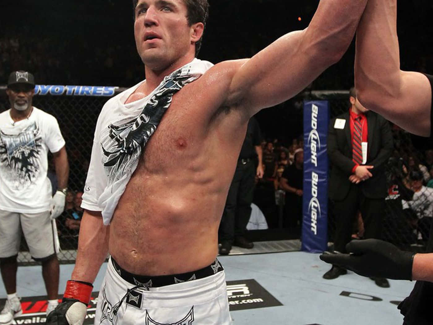 MMA拳擊手在八角籠內舉起手臂慶祝勝利。