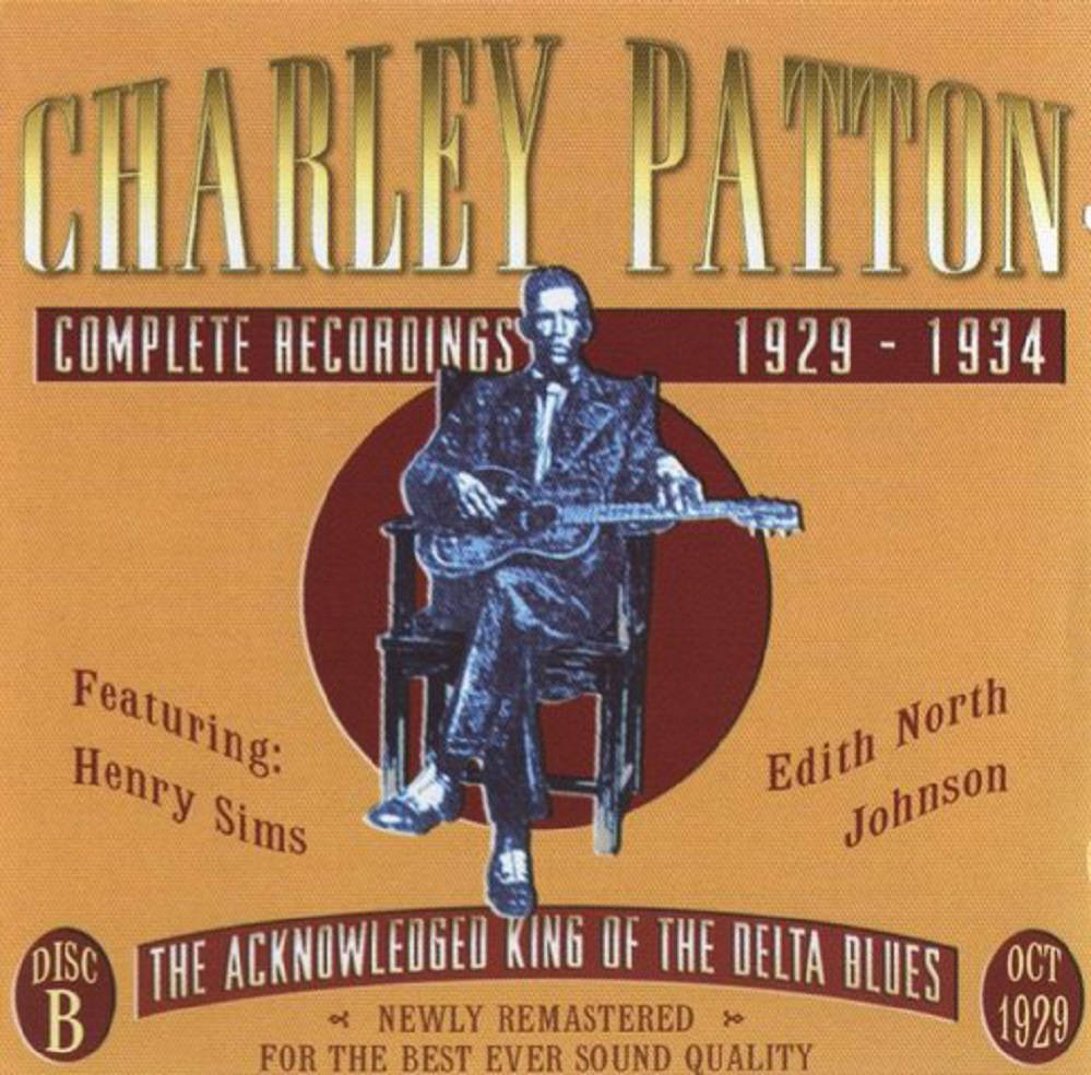 查理·帕頓1929-1934年完整錄音作品 壁紙 — Charley Patton 坐著結他的復古專輯封面，背景為溫暖的橙色，配以粗體字體。