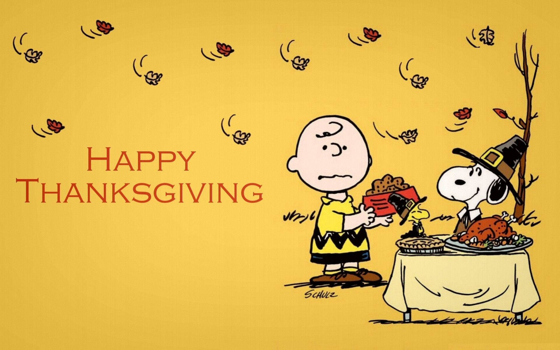 感恩節 桌布 壁紙 — 查理布朗和史努比戴著朝聖者帽子，在溫暖的黃色背景前分享感恩節大餐，有火雞派和落葉。