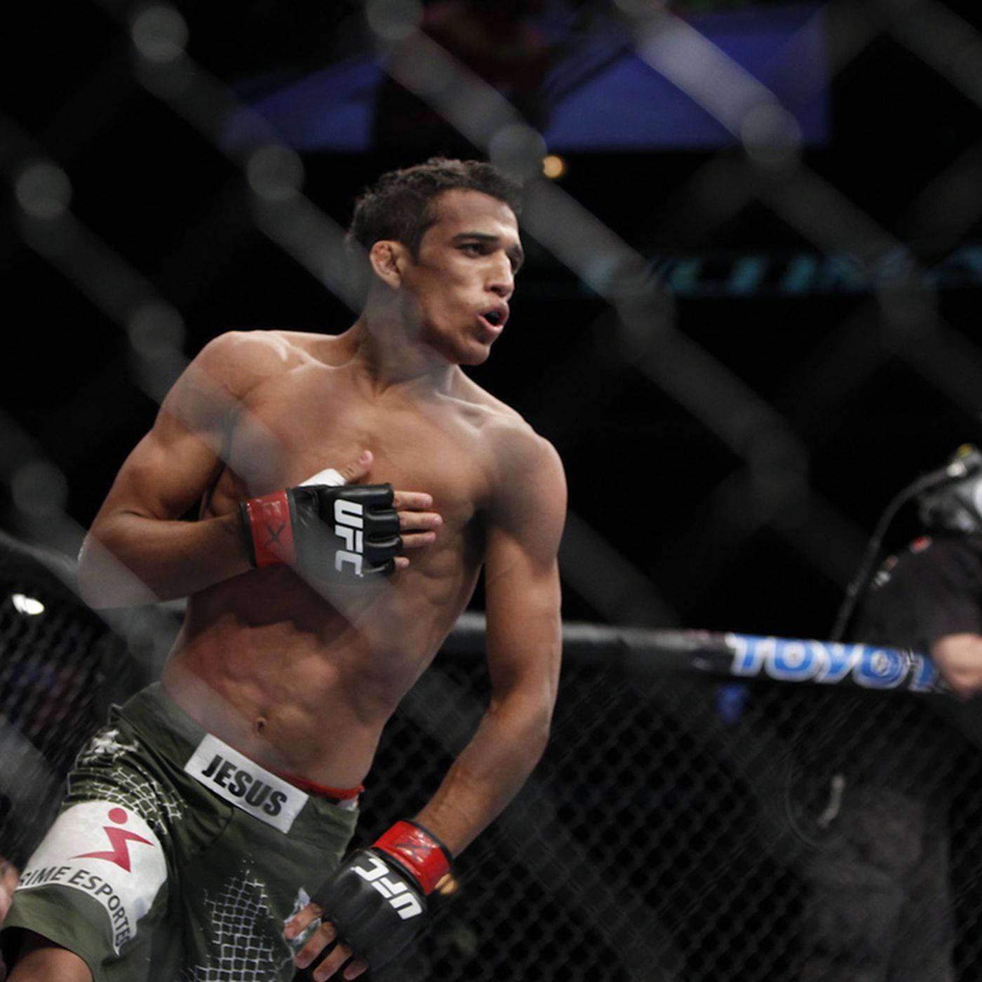 MMA選手在八角籠內將手放在胸前慶祝勝利。