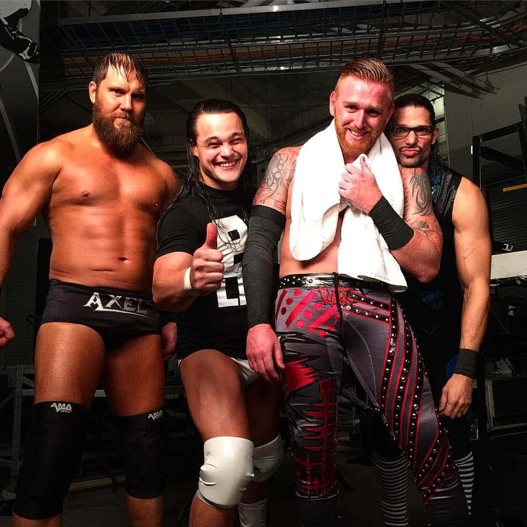 柯蒂斯·阿克爾與WWE Social Outcasts隊友 壁紙 — 四名肌肉發達的摔角手穿著擂台裝備，在後台自信地擺姿勢，面帶微笑並豎起大拇指。