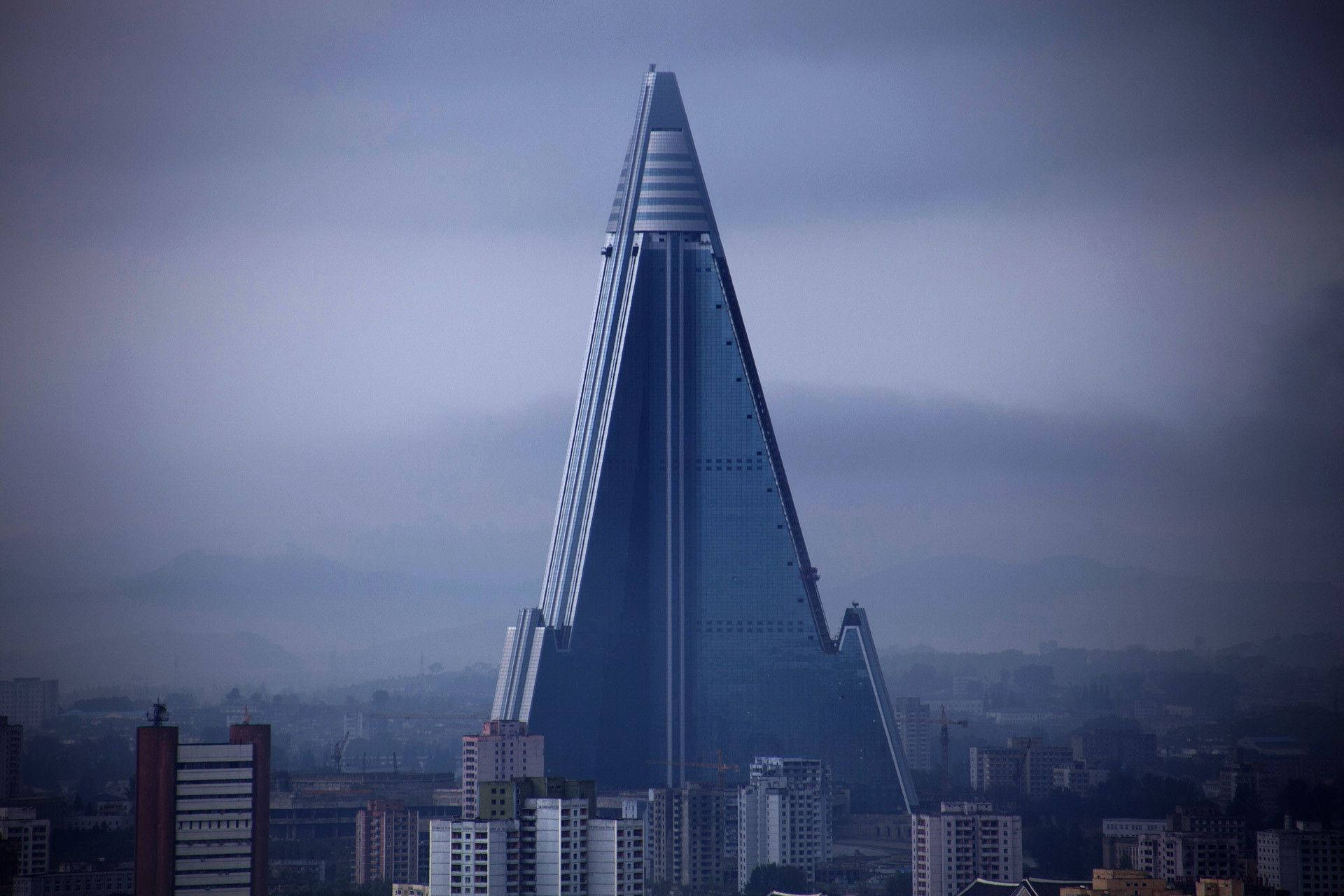 一座高大的玻璃金字塔摩天大樓在多雲的天空下主導著城市景觀。