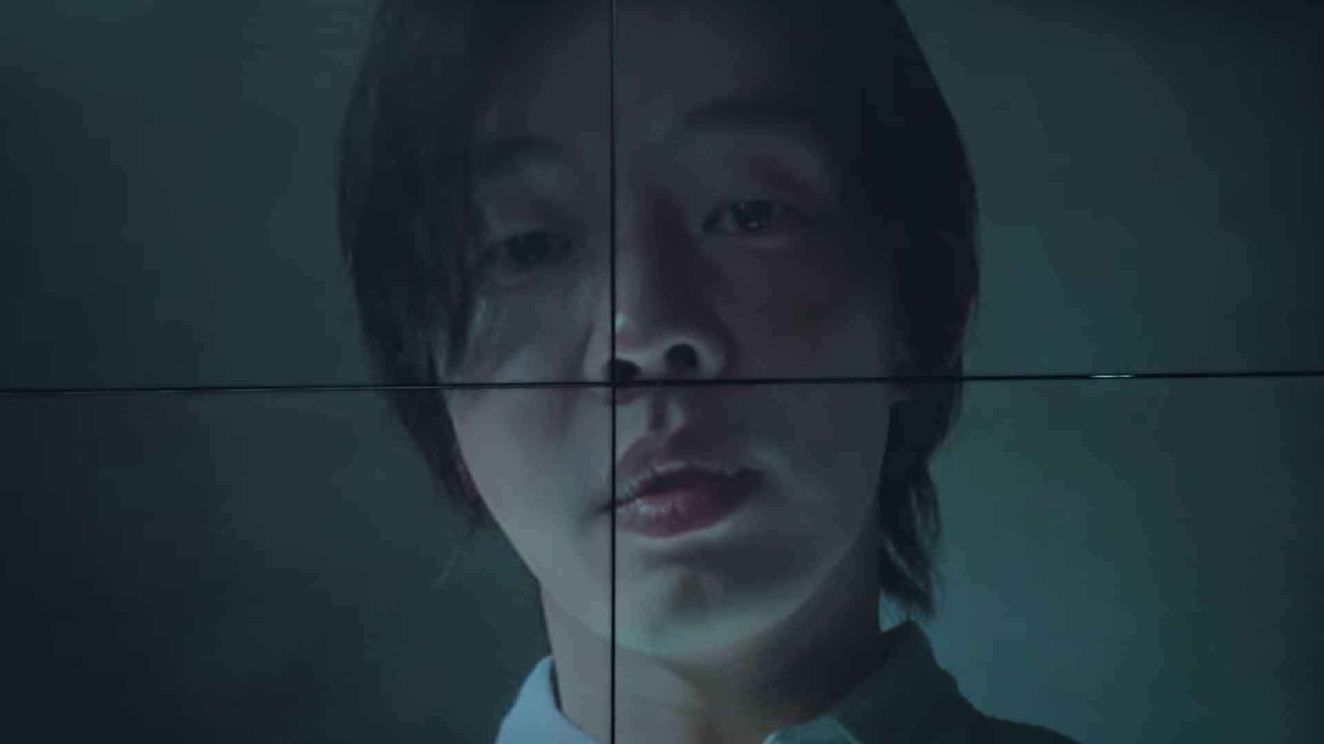 一個人的臉在昏暗的藍綠色燈光下被網格圖案分割。