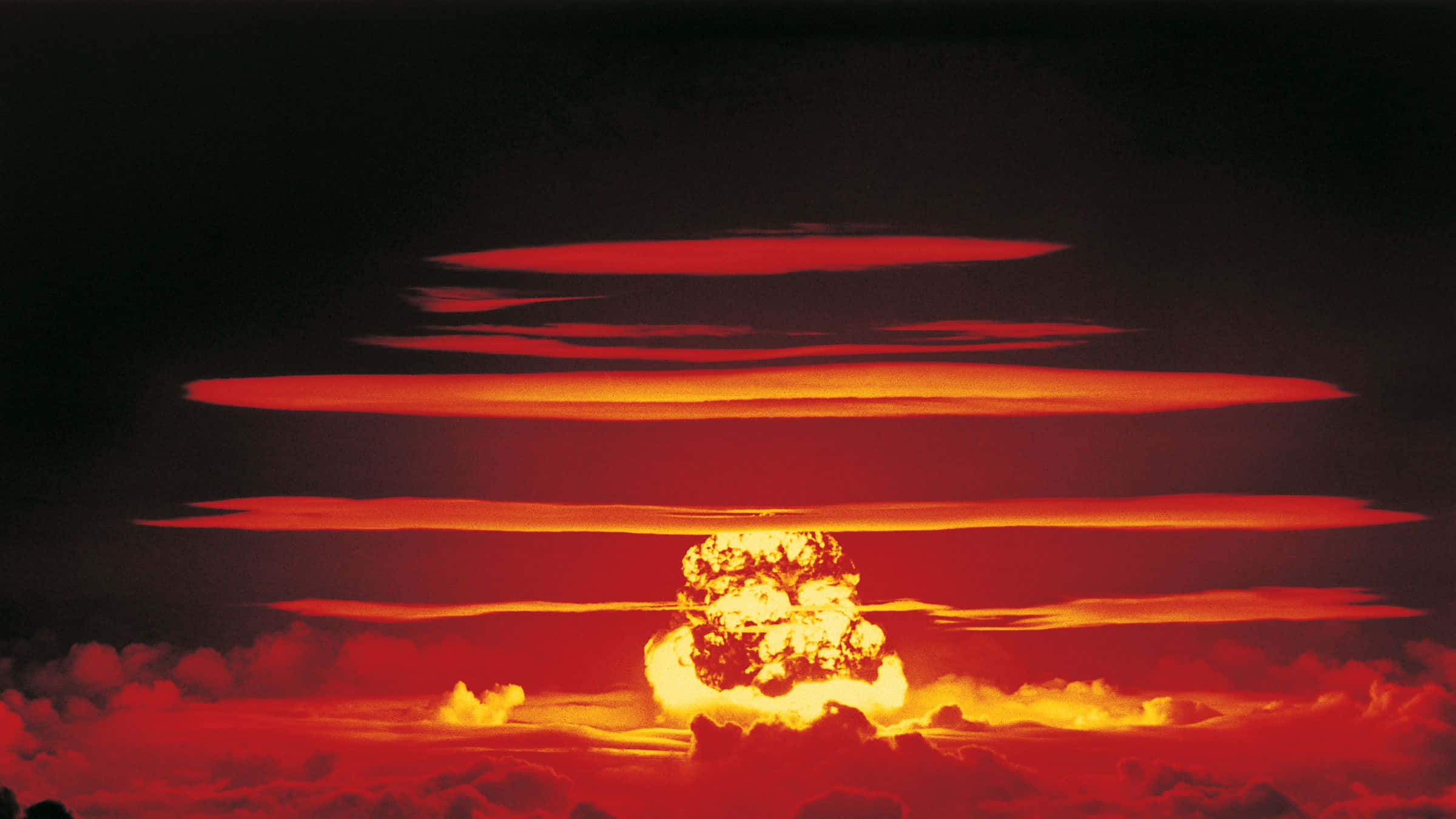 Fallout Nuke 桌布 壁紙 — 核爆炸在黑暗的天空中爆發，伴隨著熾熱的蘑菇雲，投射出強烈的紅色和橙色色調。