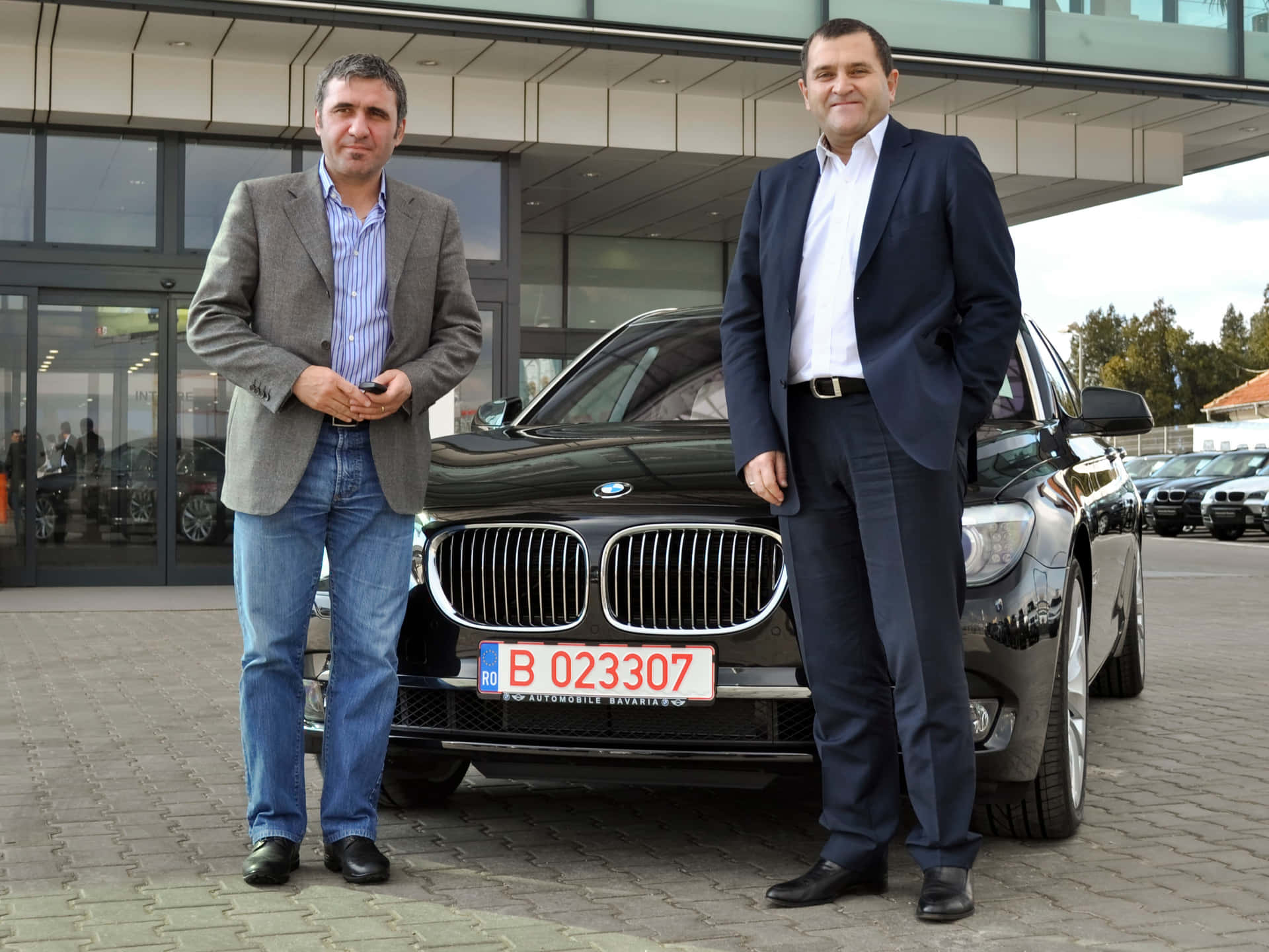 兩名男子在汽車經銷商處與黑色BMW SUV合影。