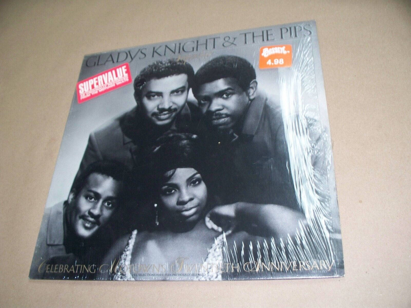 格拉迪斯·奈特與合唱團唱片 壁紙 — Gladys Knight & The Pips 的復古黑白黑膠唱片封套，密封在塑膠中，放在米色表面上。