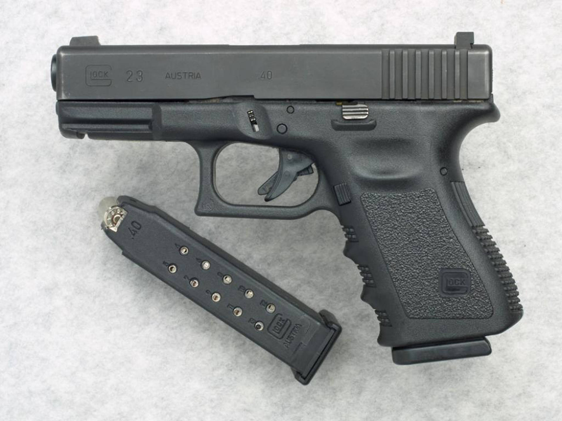 格洛克23配白大理石壁紙 壁紙 — 一支黑色Glock 23手槍連彈匣放在有紋理的灰色表面上，乾淨的攝影棚拍攝。