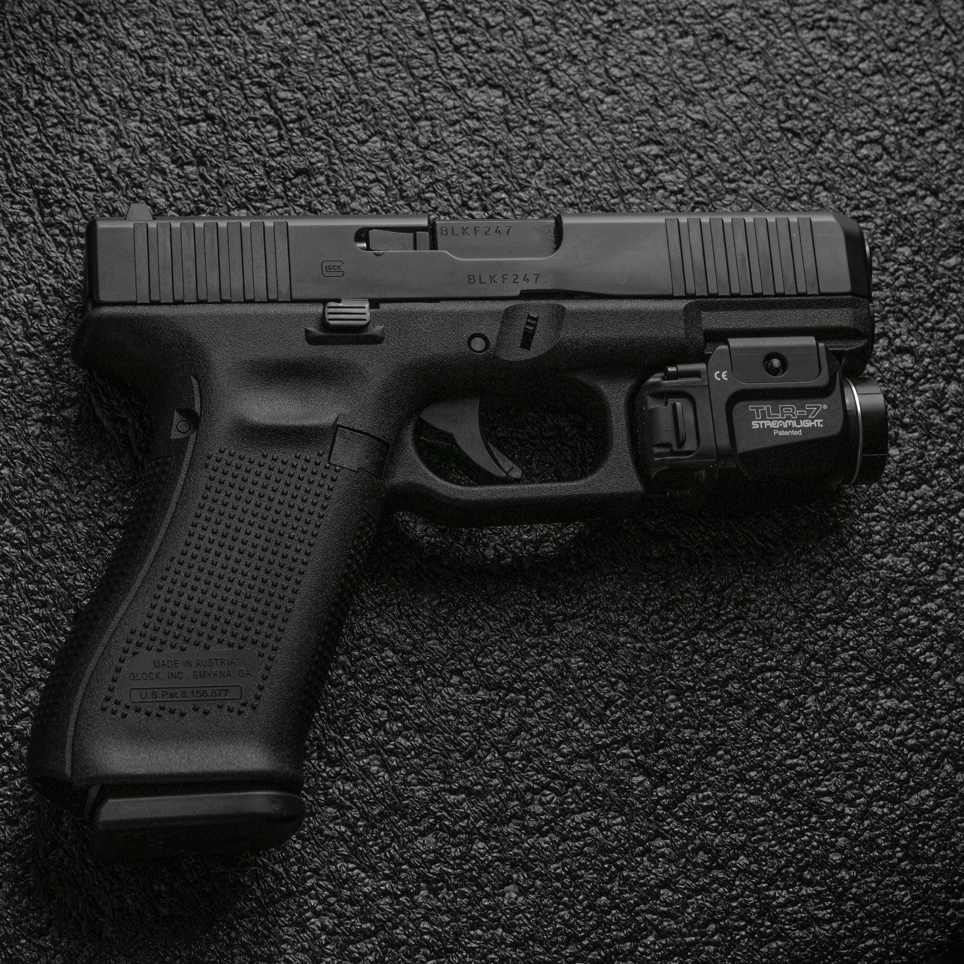 黑色 Glock 手槍配備激光瞄準器，置於紋理背景上