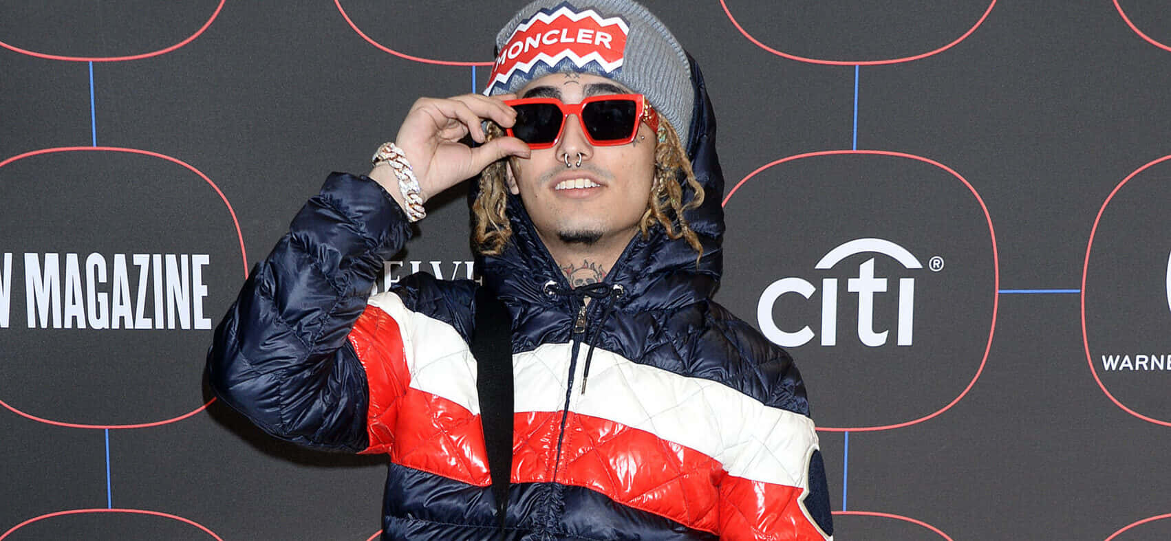 男士身穿 Moncler 外套在活動中調整紅色太陽眼鏡。