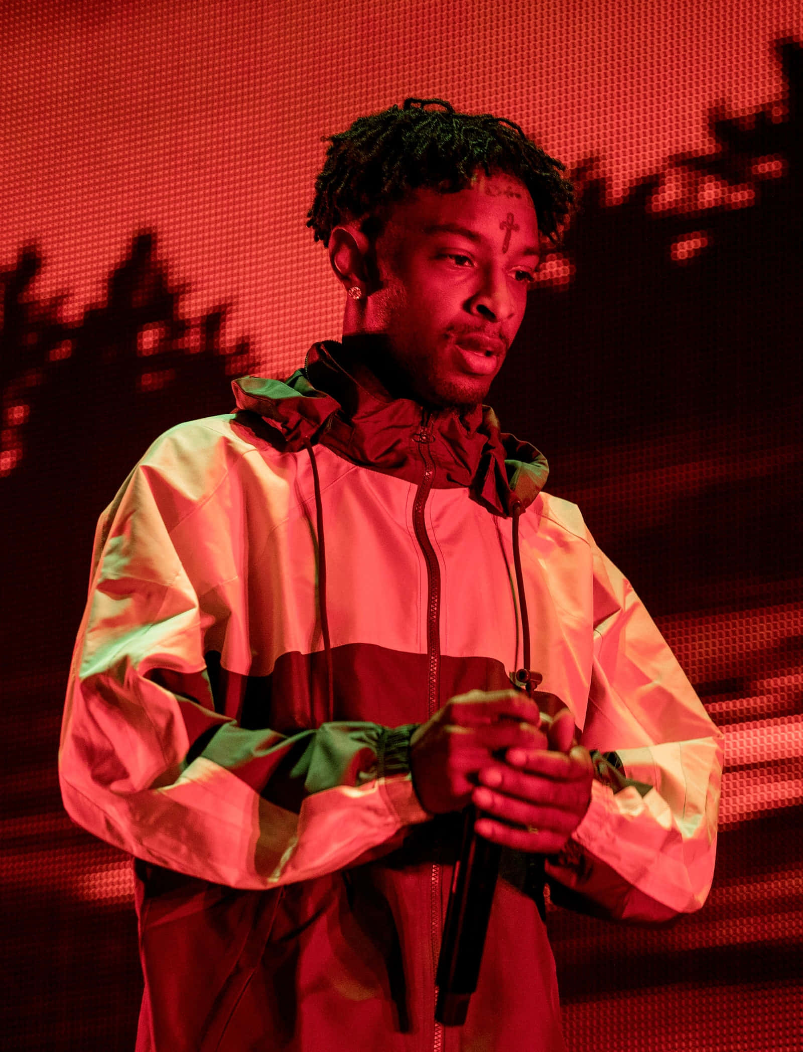 格萊美提名饒舌歌手 21 Savage 壁紙 — 一位身穿彩色外套的表演者在強烈的紅色舞台燈光下拿著麥克風，身後有陰影般的輪廓。