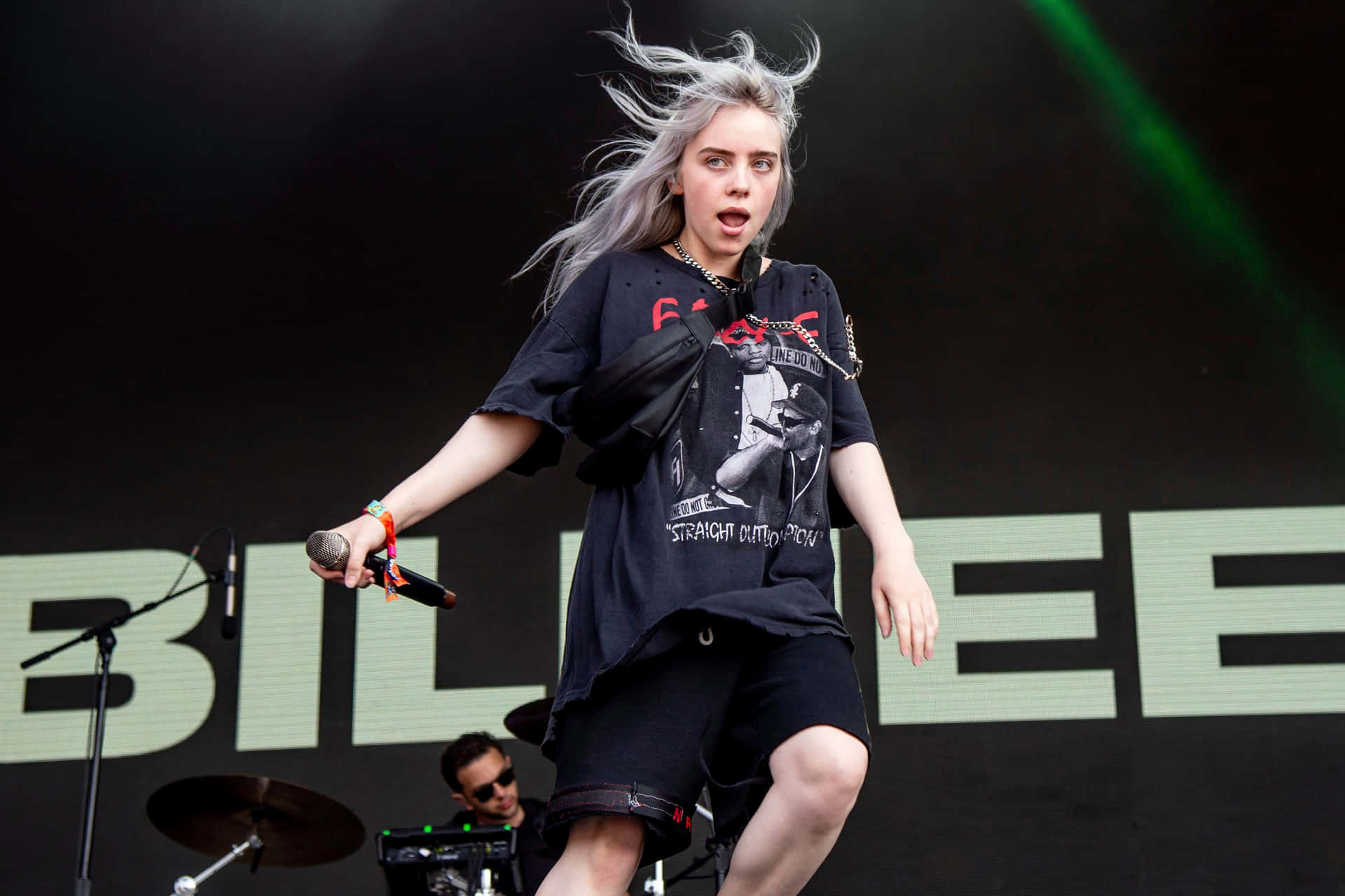 Billie Eilish 在舞台上熱情地唱歌，風吹動她的頭髮。