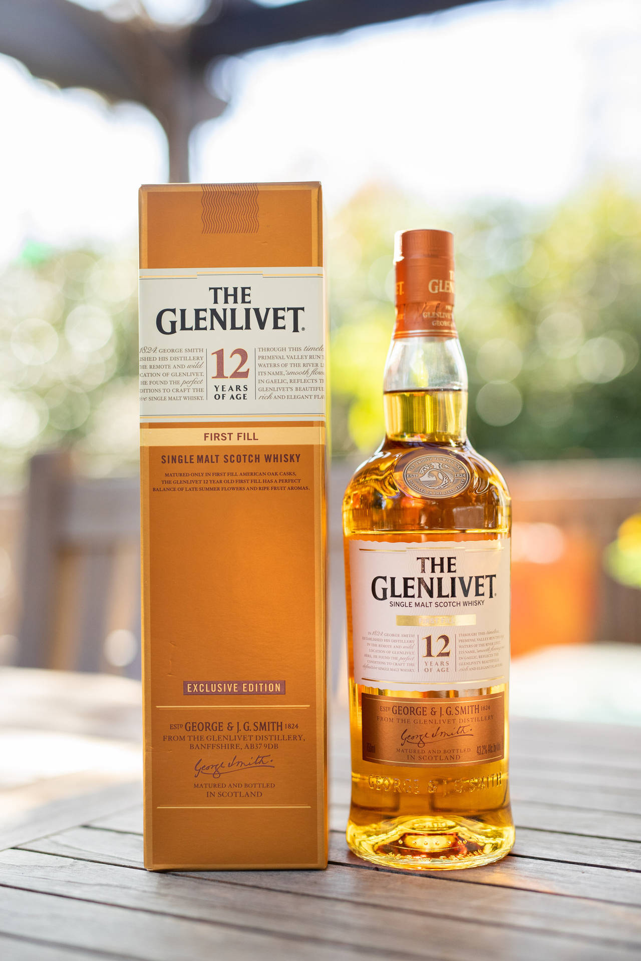 戶外木桌上的一瓶Glenlivet 12年威士忌及其盒子。
