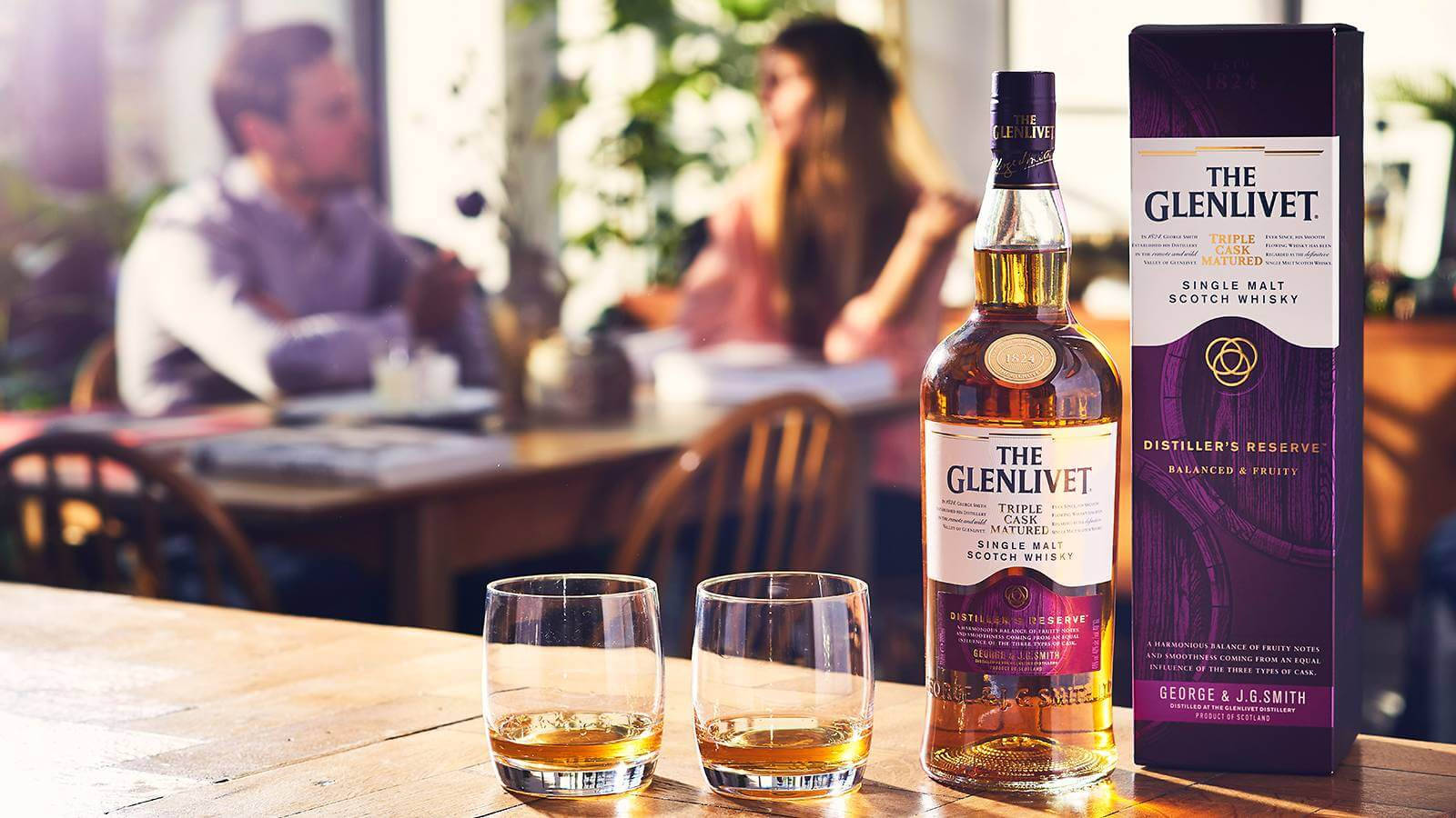 餐廳木桌上的一瓶Glenlivet威士忌和兩個酒杯。