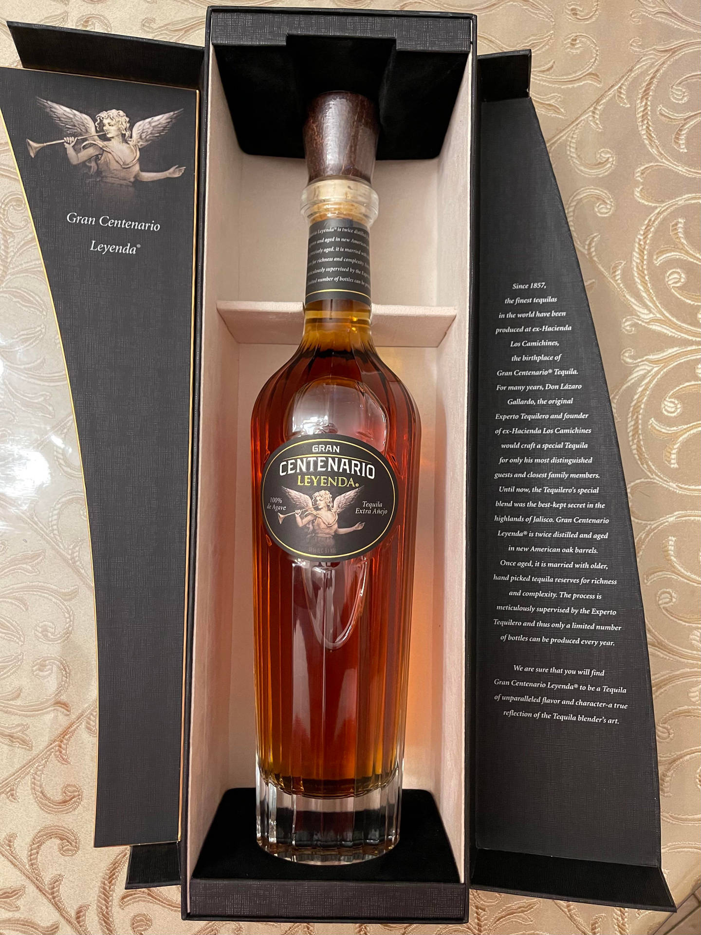 Gran Centenario Leyenda 龍舌蘭酒瓶放在黑色豪華盒子中，置於圖案布料上。