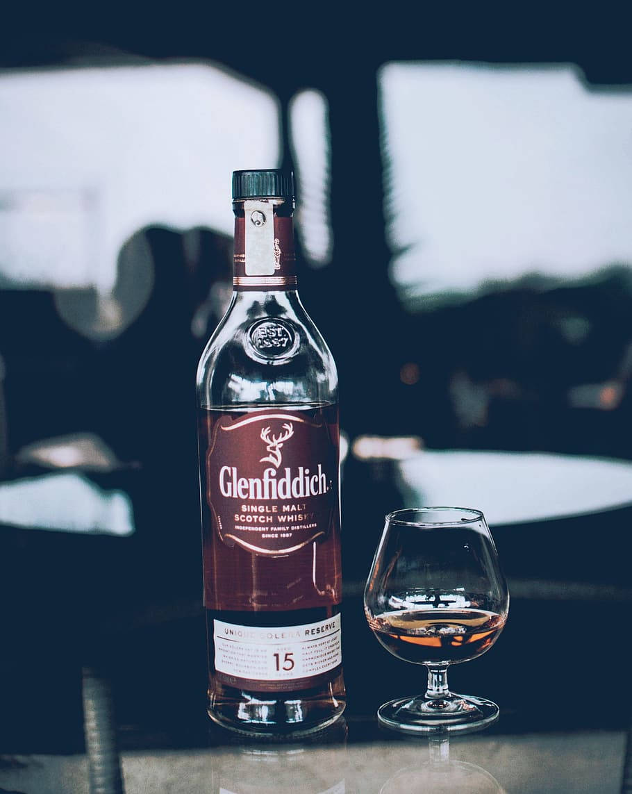 Glenfiddich 15 年威士忌瓶和玻璃杯在反光表面上。