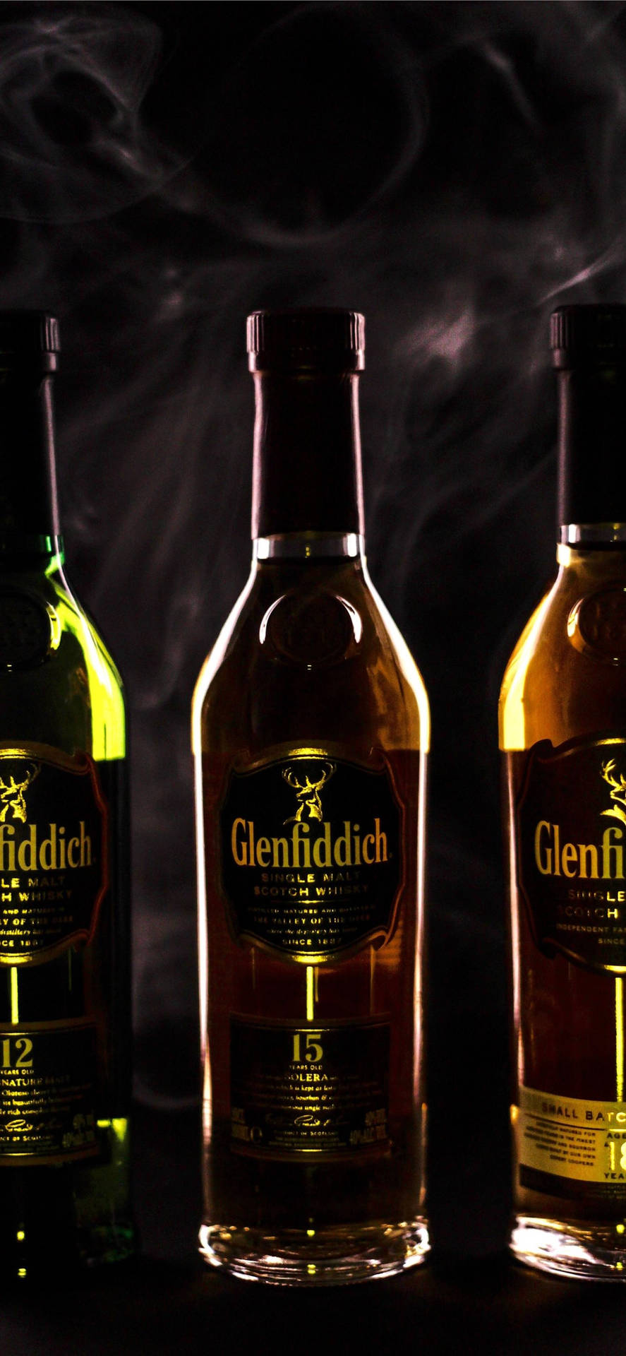 三瓶 Glenfiddich 威士忌在黑暗環境中帶有煙霧。