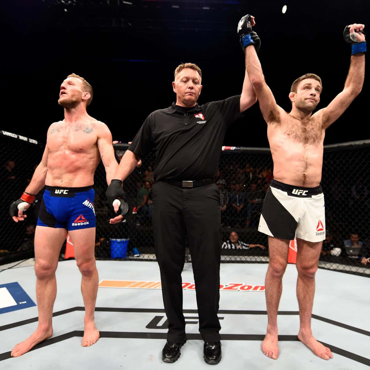 格雷·梅納德賽後決賽結果 壁紙 — UFC裁判在八角籠中舉起勝利的拳手的手臂，而對手在場館燈光下敗北站立。