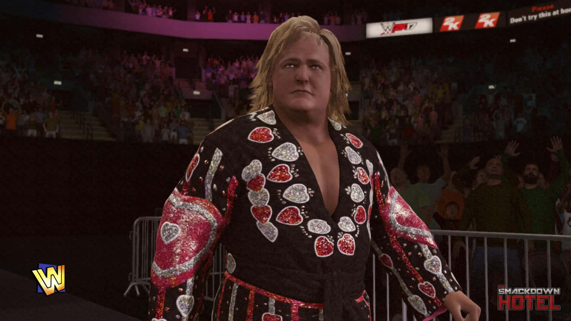 格雷格·瓦倫丁 WWE 2K17 名單 壁紙 — 穿著心形圖案外套的摔角手自信地站在競技場上，身後有歡呼的人群在路障後面。