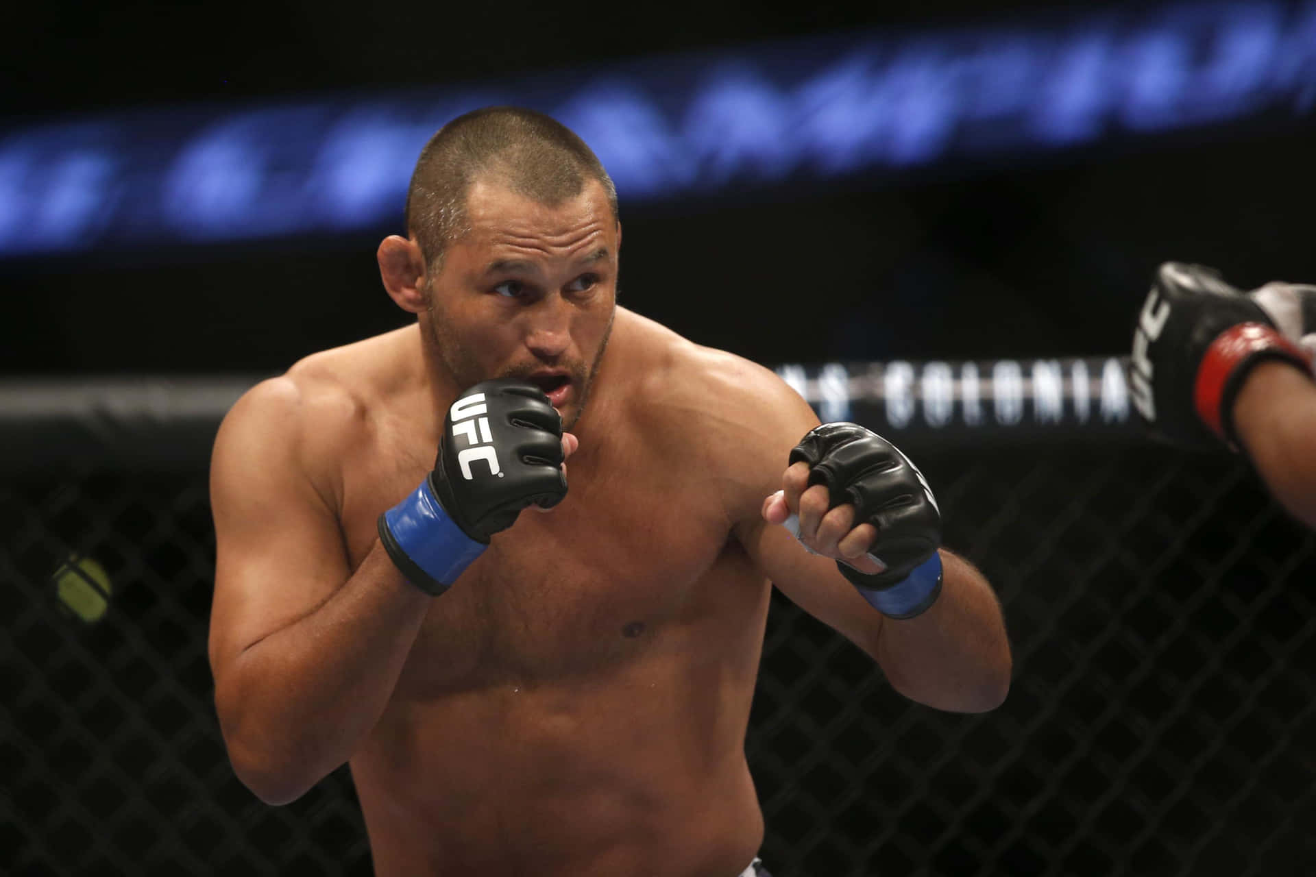 MMA拳手在籠內進行激烈比賽，戴著黑色UFC手套