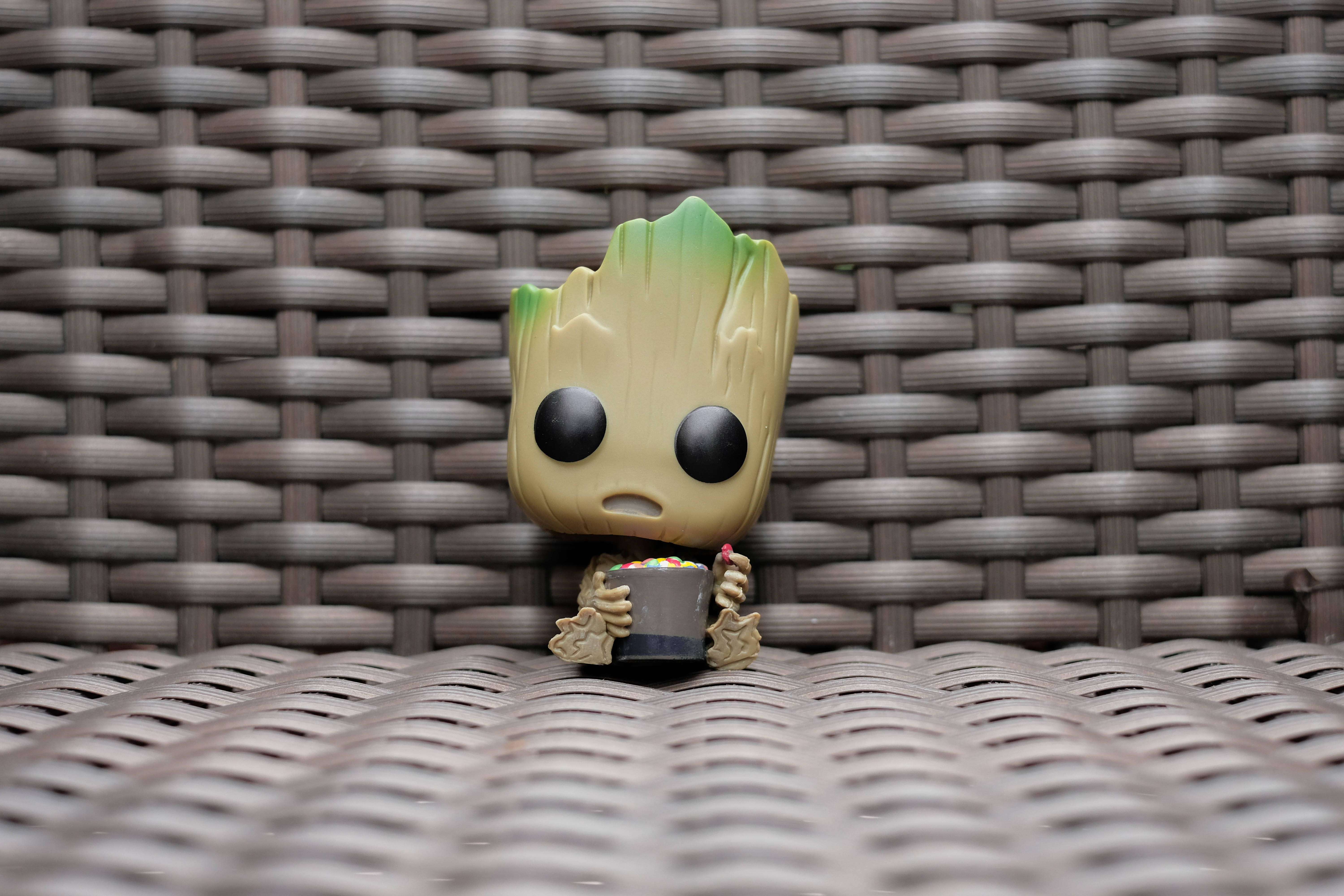 格魯特 Funko Pop 模型 壁紙 — 一個細小的Groot Funko Pop公仔坐在一張編織的棕色戶外椅子上，拿著一杯色彩繽紛的糖果。