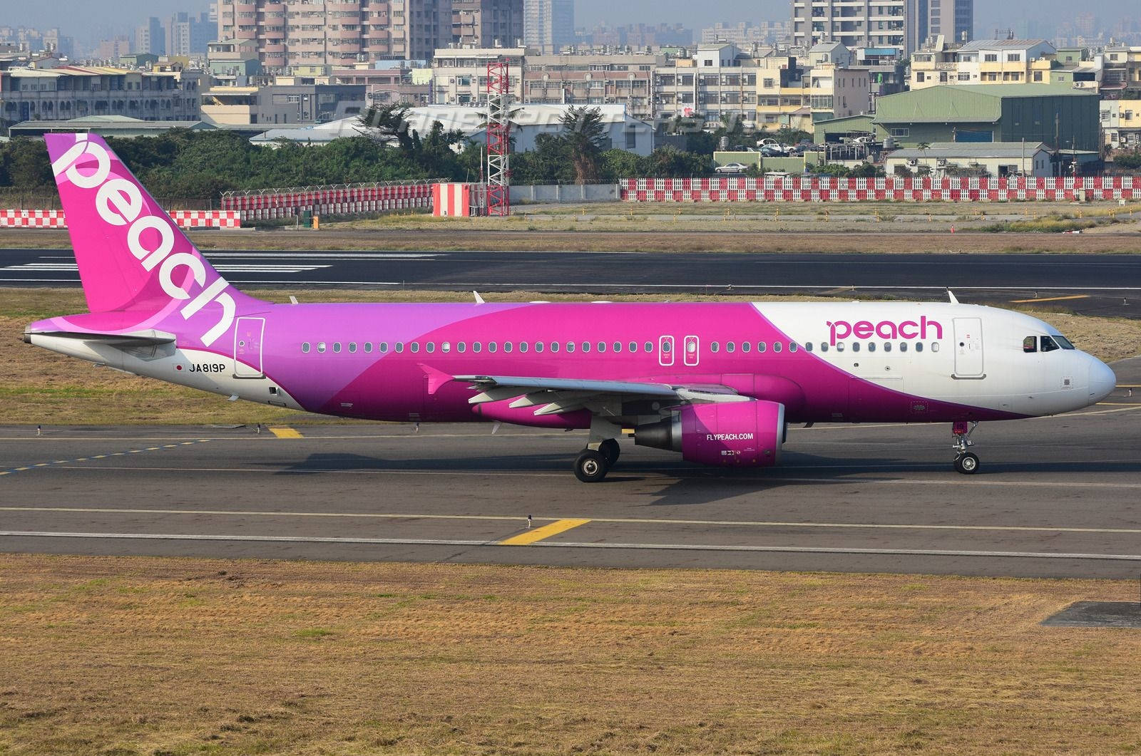 Peach Airlines飛機在跑道上，背景有城市天際線