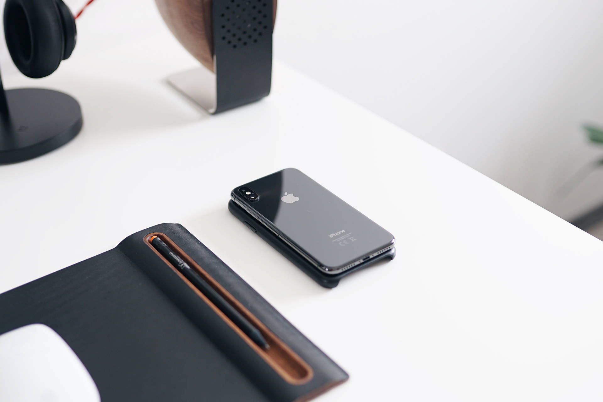 白色桌子上的黑色iPhone，配有耳機和揚聲器