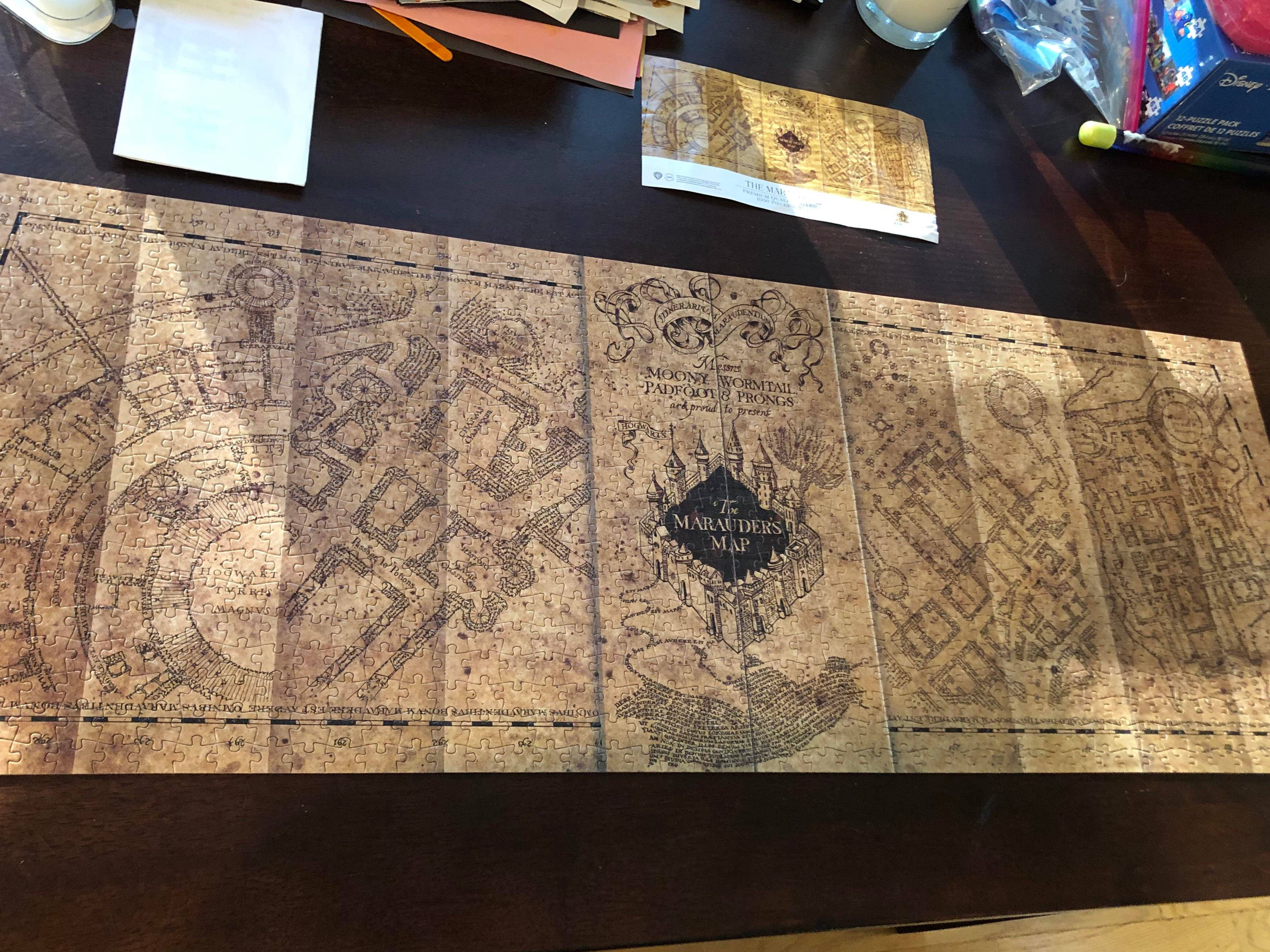 桌上的掠奪者地圖 壁紙 — 完成嘅劫盜地圖拼圖平放喺深色木枱上，周圍係手工材料。