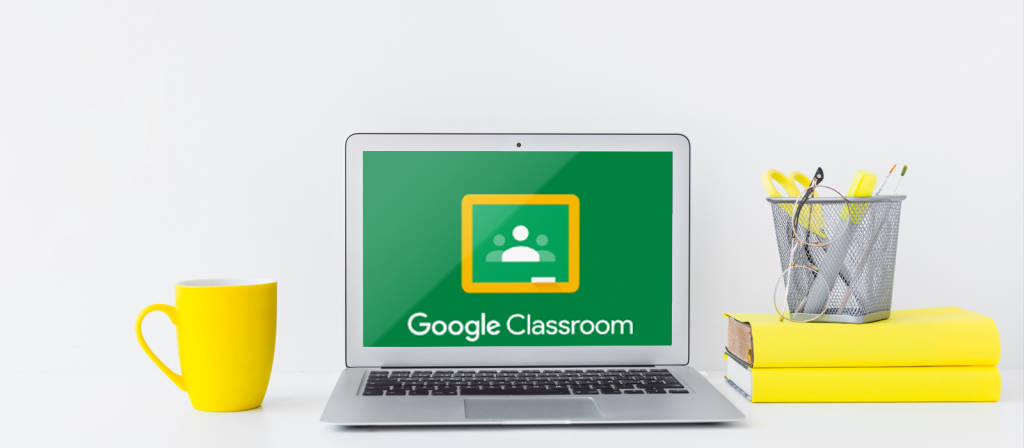 桌上筆電搭配 Google Classroom 壁紙 — 一部銀色手提電腦在綠色屏幕上顯示Google Classroom，旁邊有一個黃色杯、疊起的黃色文件夾和筆筒。