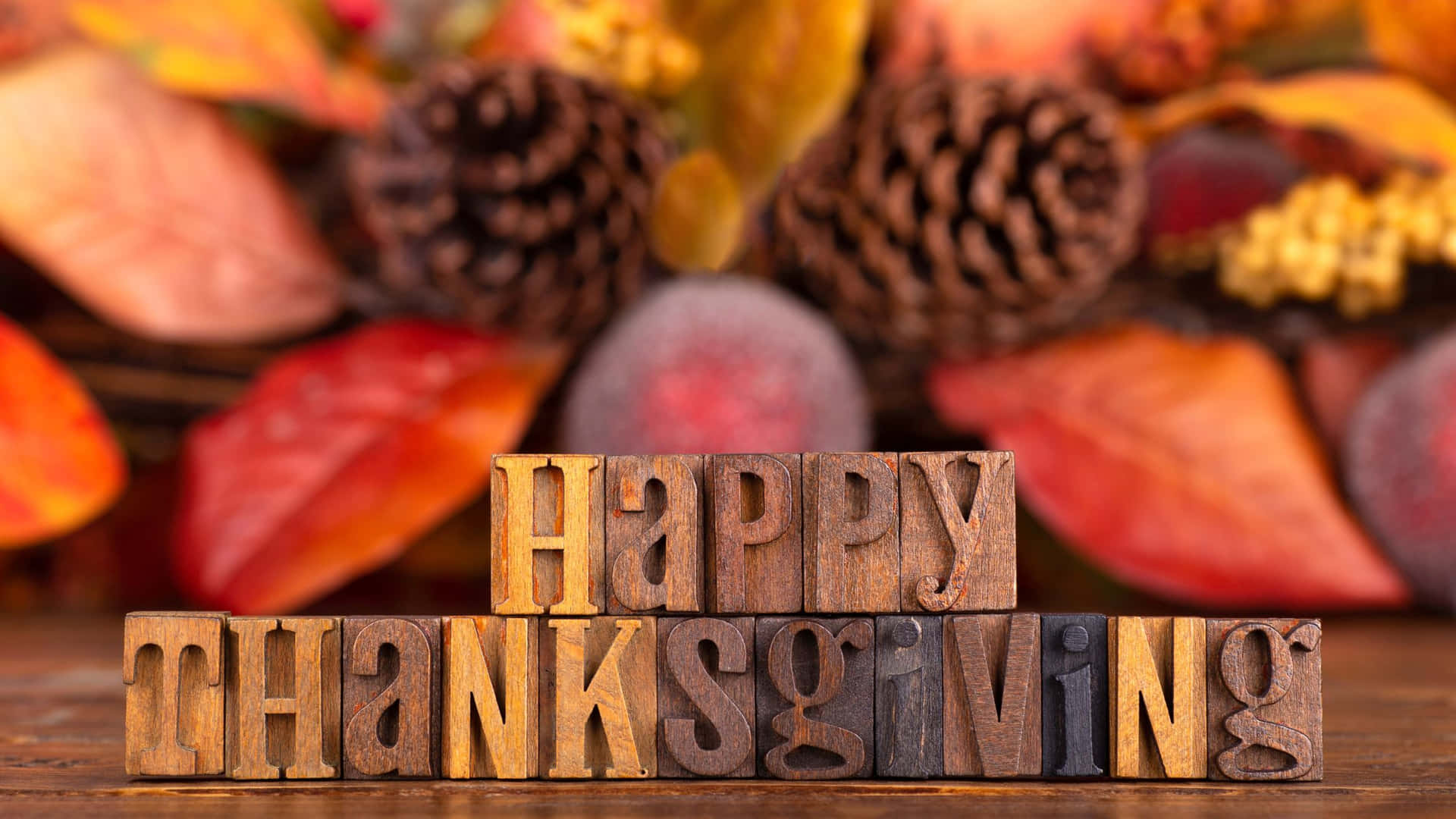 木製方塊被秋葉和松果環繞，拼出Happy Thanksgiving。