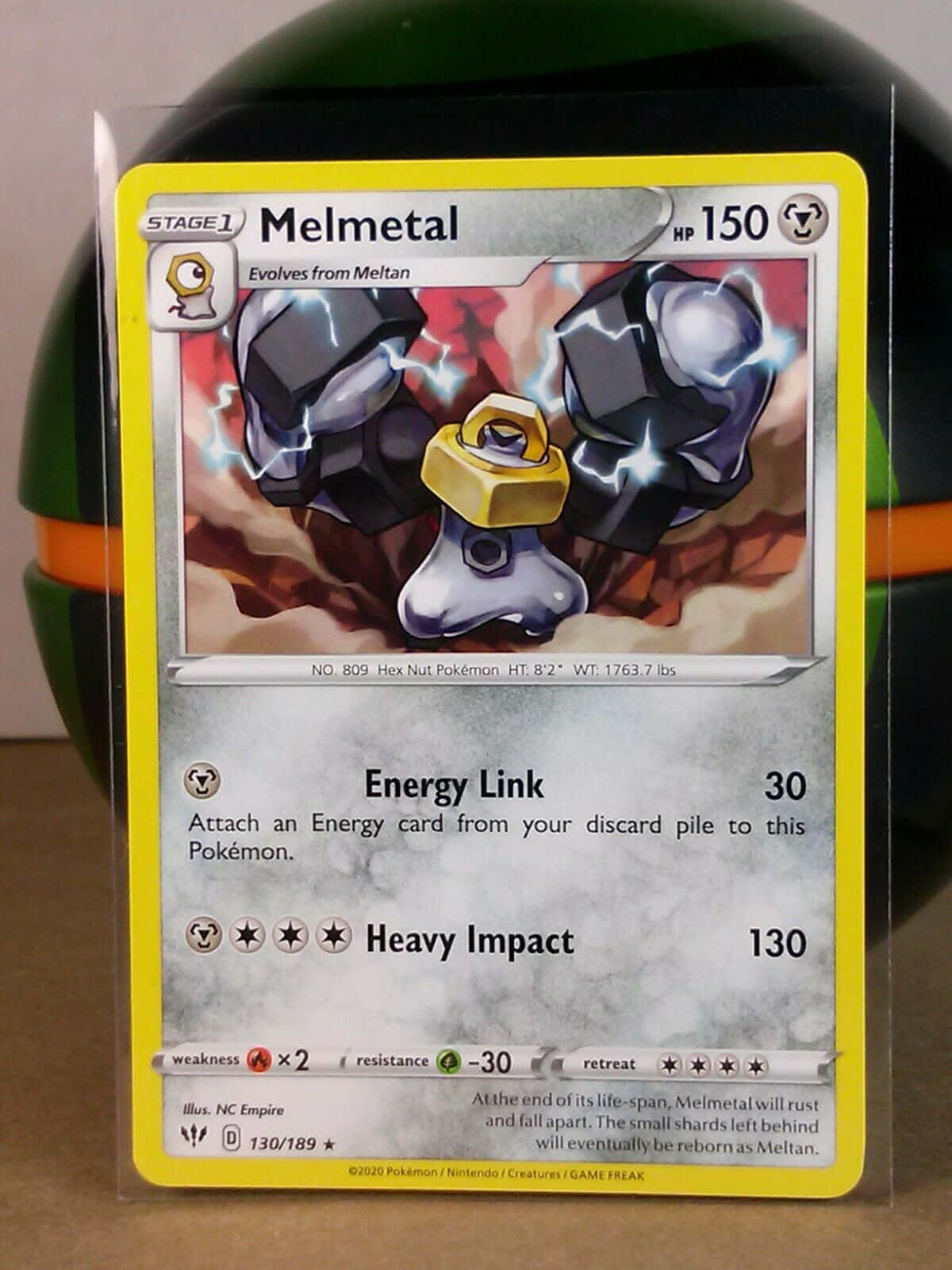 一張 Melmetal 的寶可夢集換式卡牌， Melmetal 是帶有閃電效果的金屬機械寶可夢。