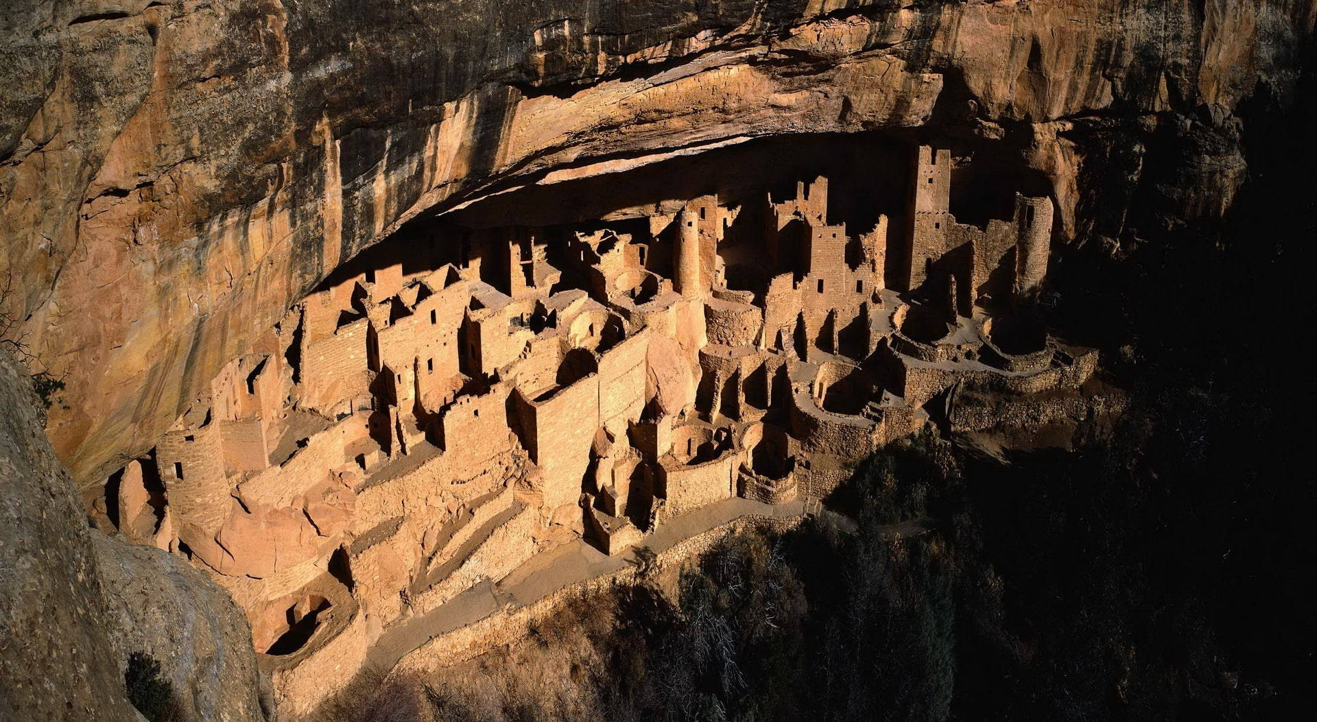 金色陽光下，砂岩中雕刻的古代懸崖住所遺址。