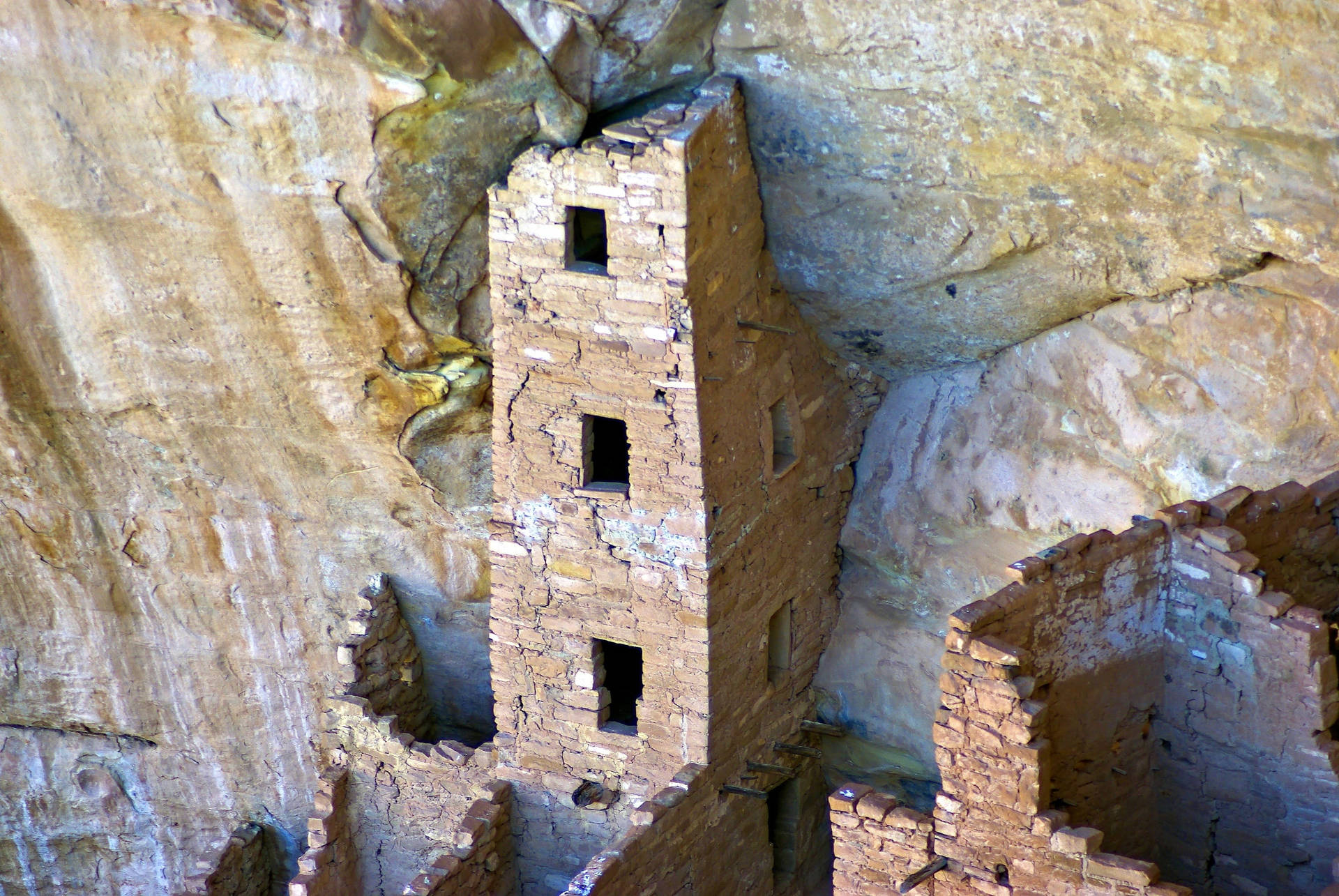 建在砂岩懸崖上的古代懸崖住宅遺址，帶有石牆和方形窗戶。