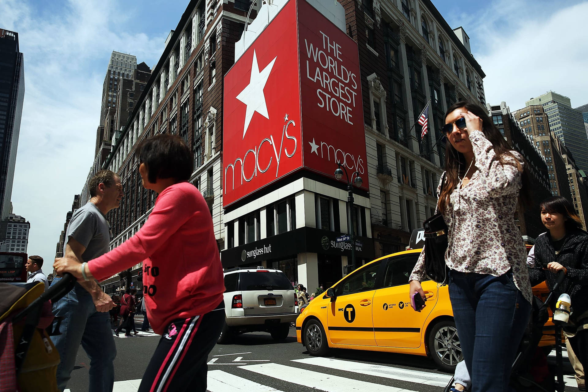 人們在黃色出租車和 Macy's 商店標誌的背景下穿過紐約繁忙的街道。