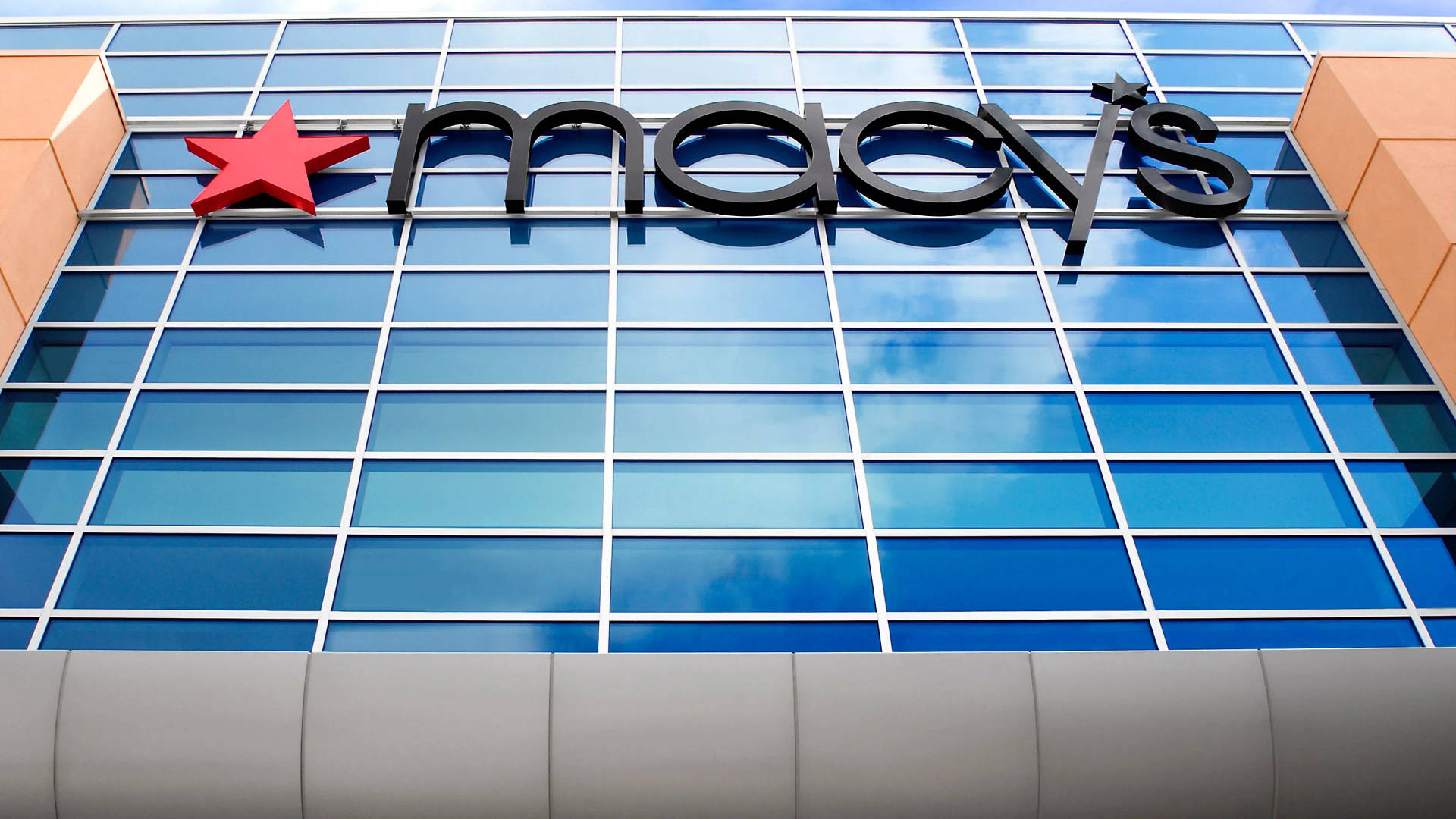 Macy's百貨公司招牌在玻璃建築外牆上，帶有天空倒影。