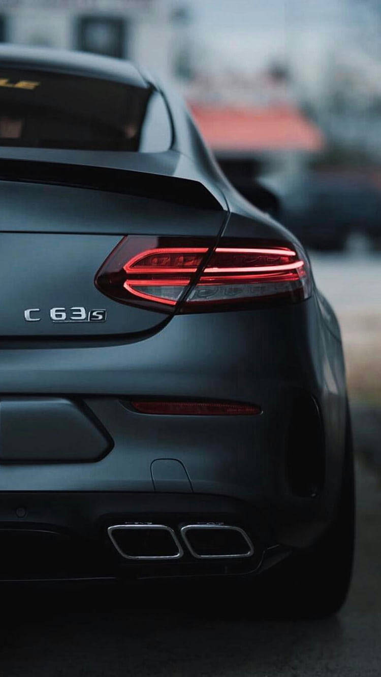 啞黑色 Mercedes-AMG C63 S 跑車的後視圖，帶有發光的紅色尾燈和雙排氣管。