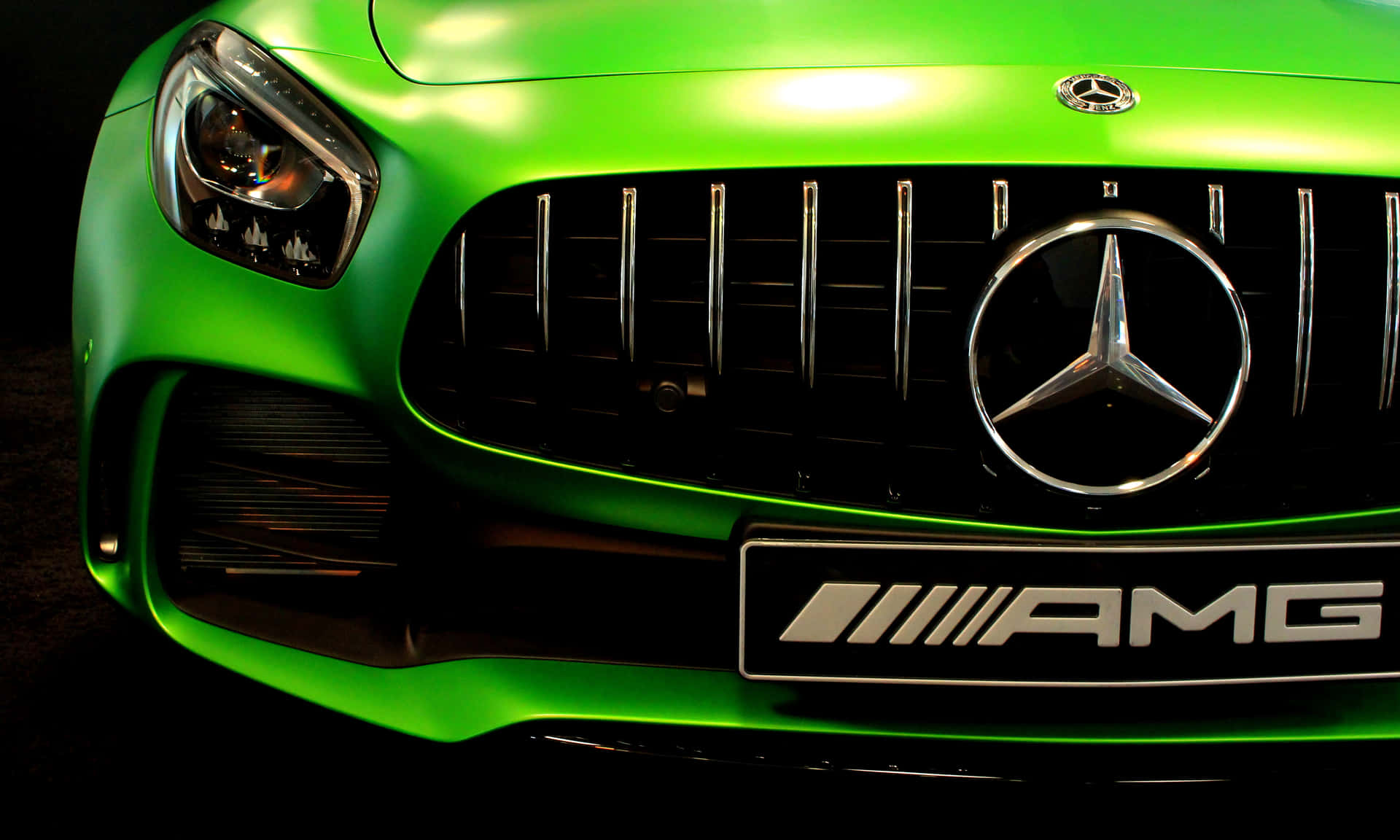 綠色 Mercedes-AMG 汽車的前格柵和標誌的特寫。