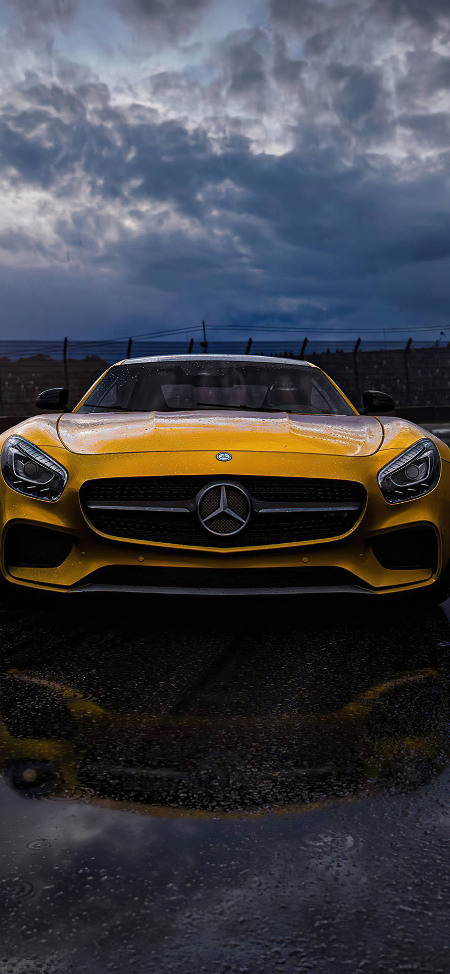 暴風雲下濕滑路面上的黃色 Mercedes-AMG GT 跑車。