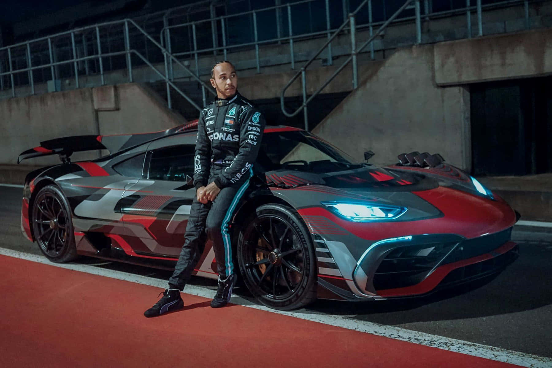 劉易斯·咸美頓在夜間賽道上與他的AMG One超跑合影。