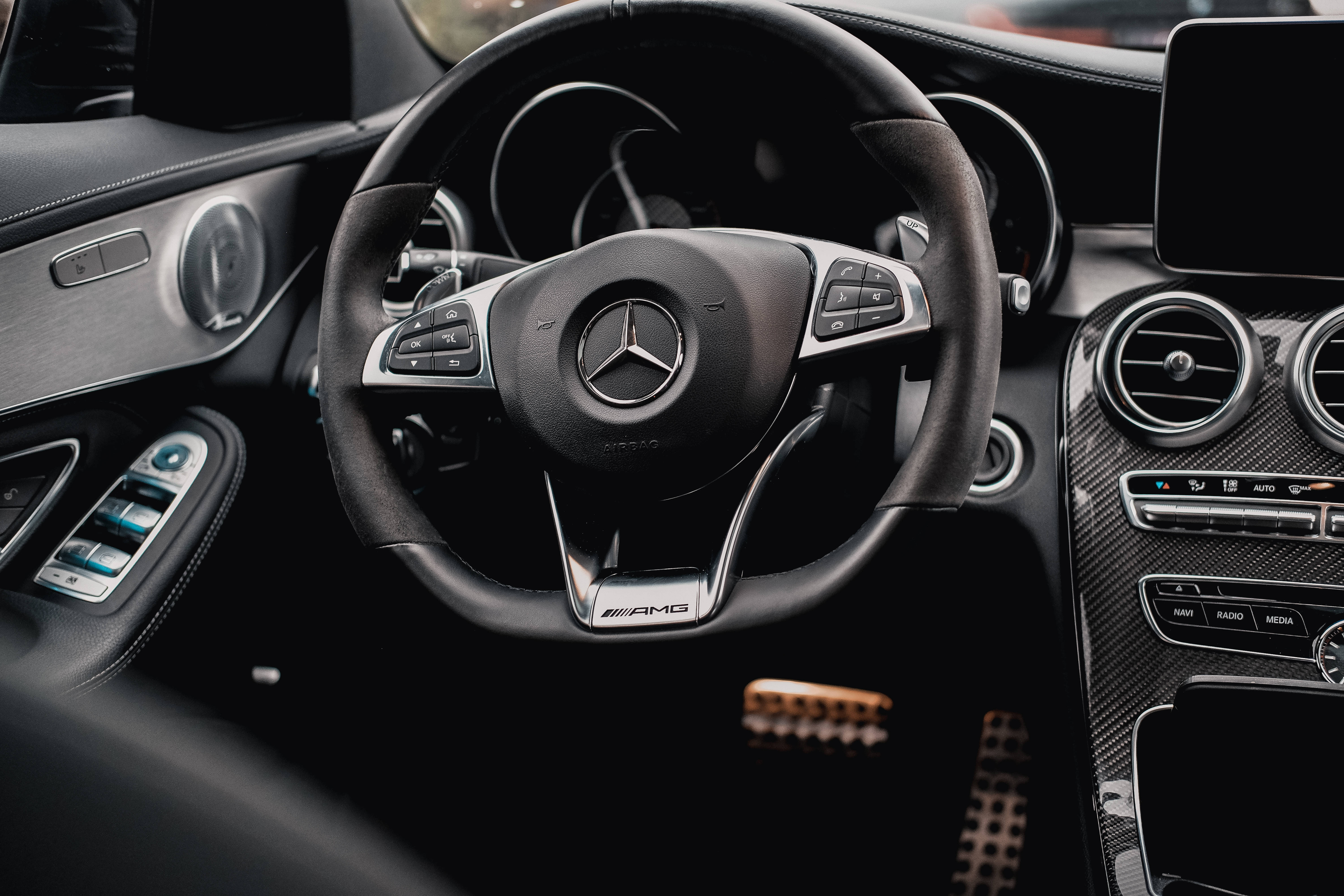 梅賽德斯-AMG 方向盤 壁紙 — 近距離拍攝時尚黑色 Mercedes-AMG 方向盤，帶有碳纖維裝飾和數碼儀表板。