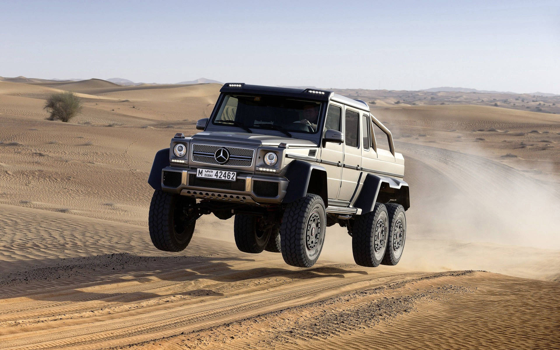 銀色梅賽德斯 G63 AMG 6x6 在沙漠中跳過沙丘。