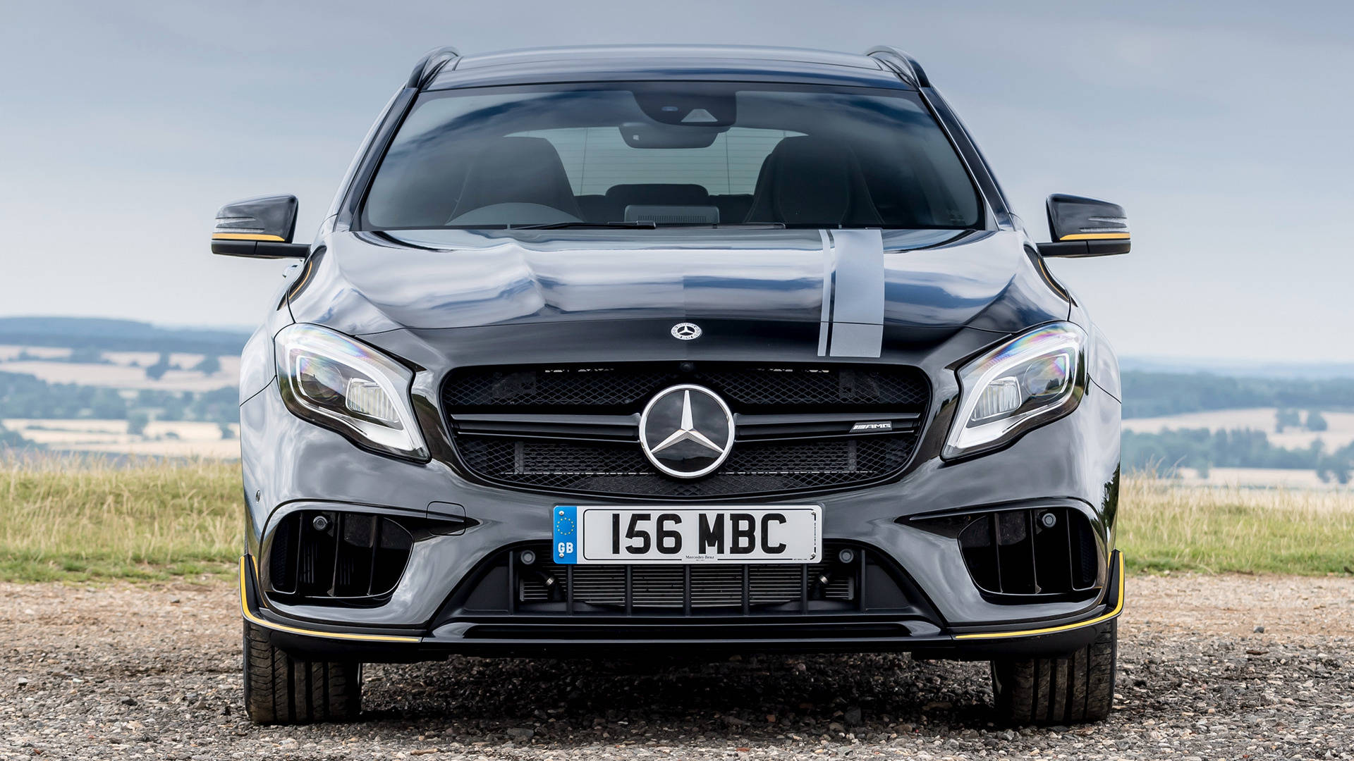 銀色 Mercedes-AMG A45 S 停泊在碎石路上，以山丘為背景。