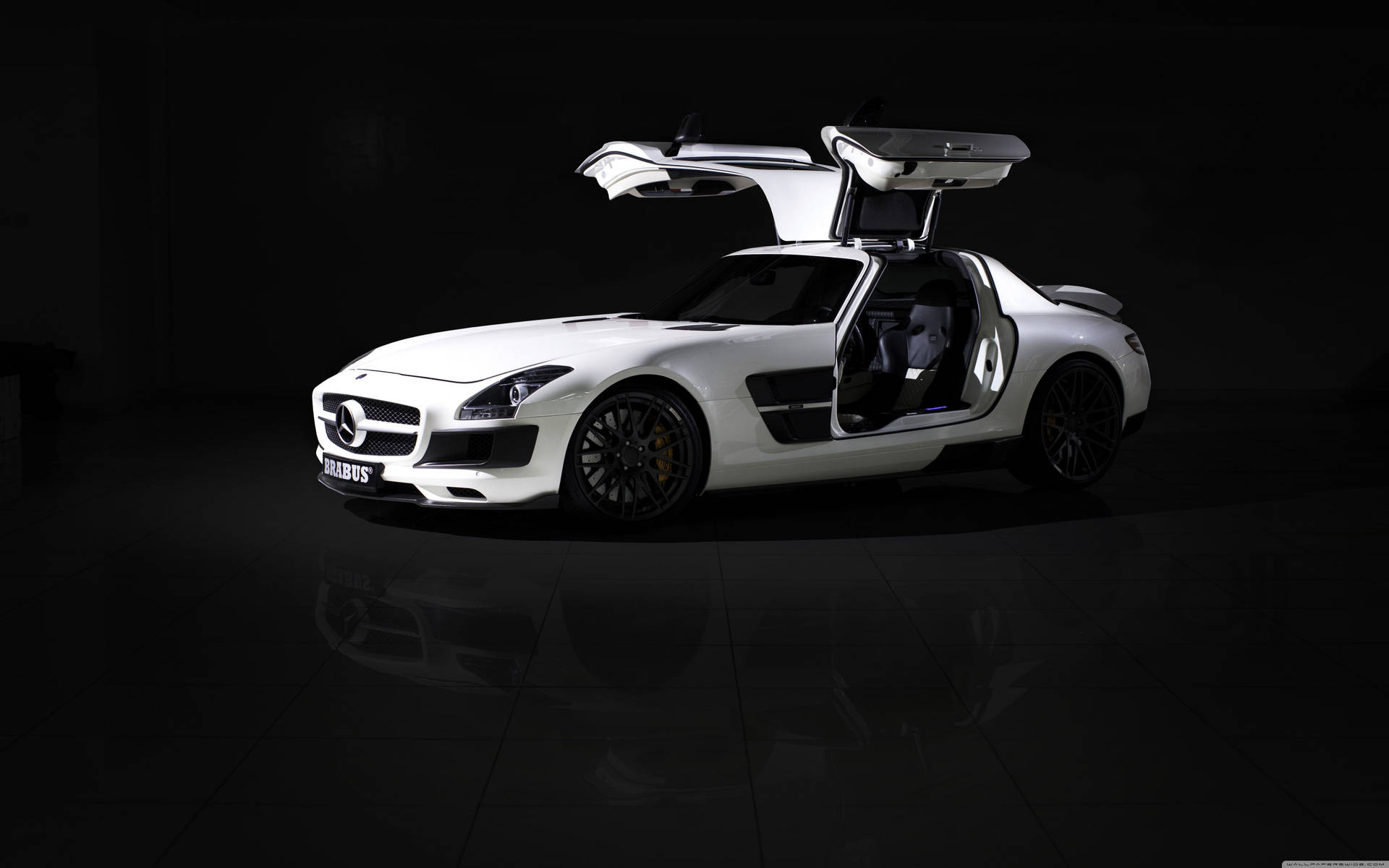 白色平治 SLS AMG 鷗翼門打開，在黑暗攝影棚中反射地板。