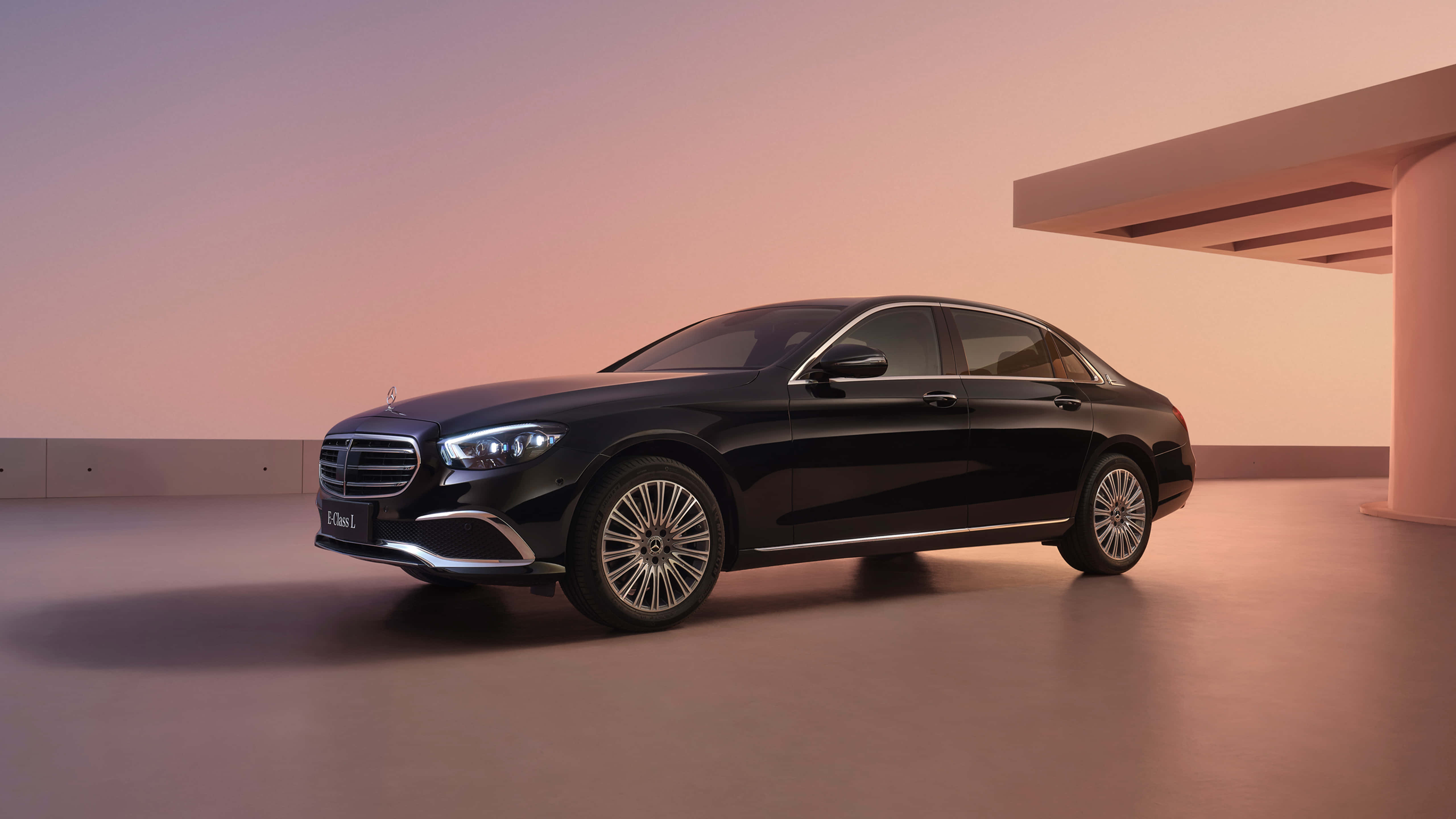 梅賽德斯-奔馳E級車於黃昏時分 壁紙 — 一輛時尚的黑色 Mercedes-Maybach S-Class 轎車在溫暖的暮色燈光下，於極簡現代建築環境中閃耀。