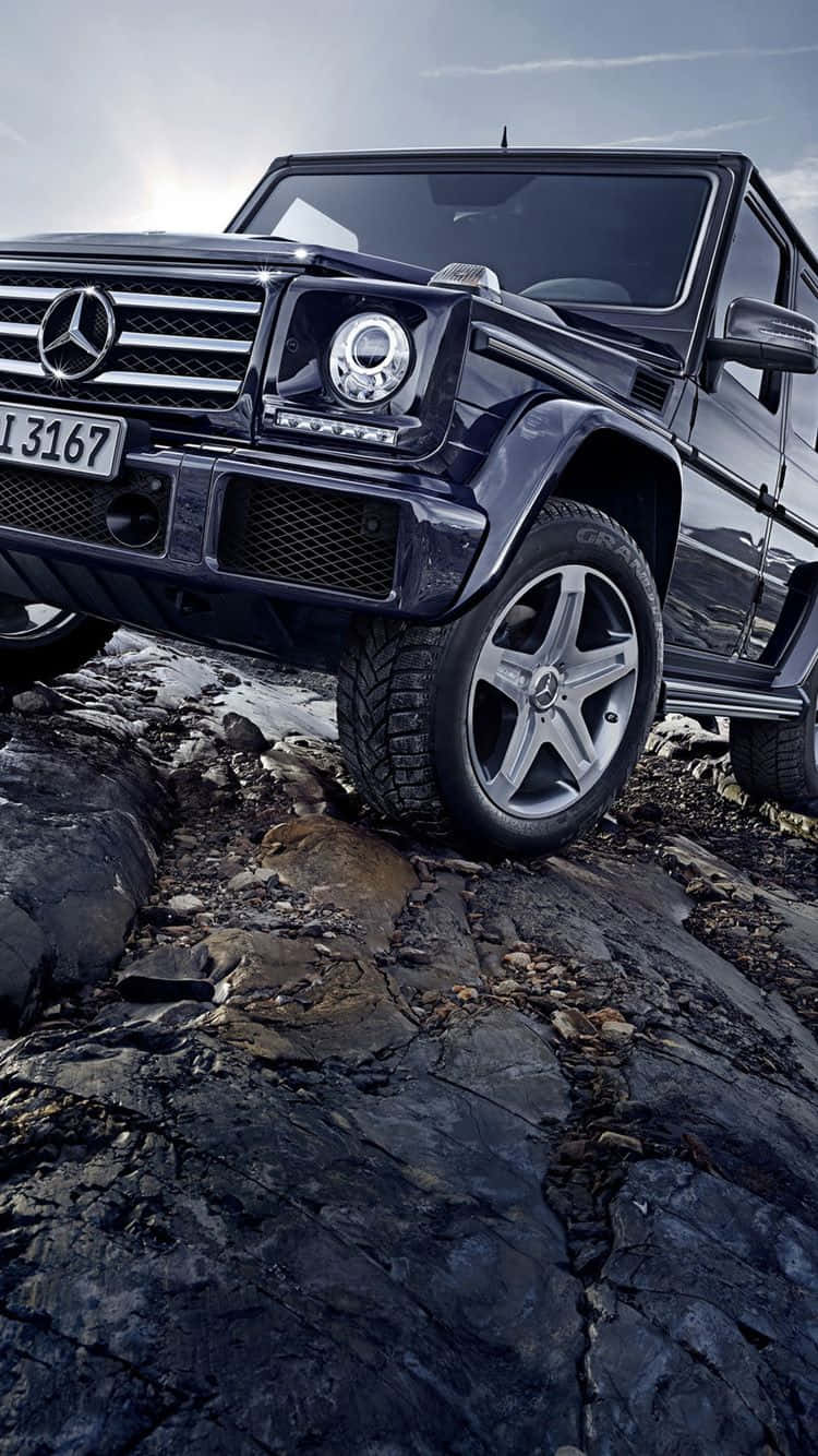 黑色 Mercedes G-Class SUV 在黃昏時分行駛於岩石地形。
