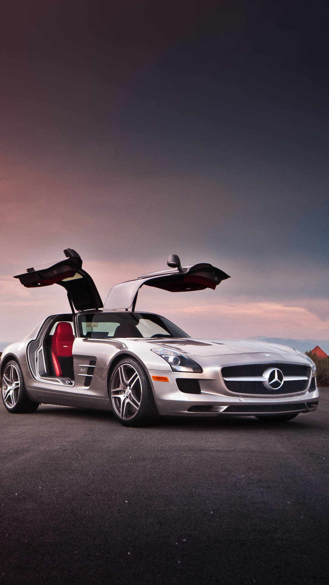 銀色平治 SLS AMG 在日落時分打開鷗翼車門停在瀝青路上。