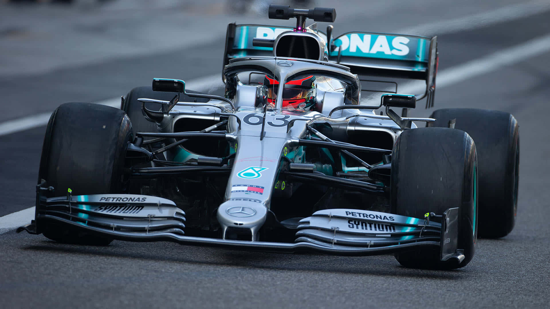 梅賽德斯AMG馬石油隊HD F1 2019賽道縮放背景 壁紙 — 一輛時尚的銀色和青色63號一級方程式賽車在潮濕的瀝青賽道上奔馳。